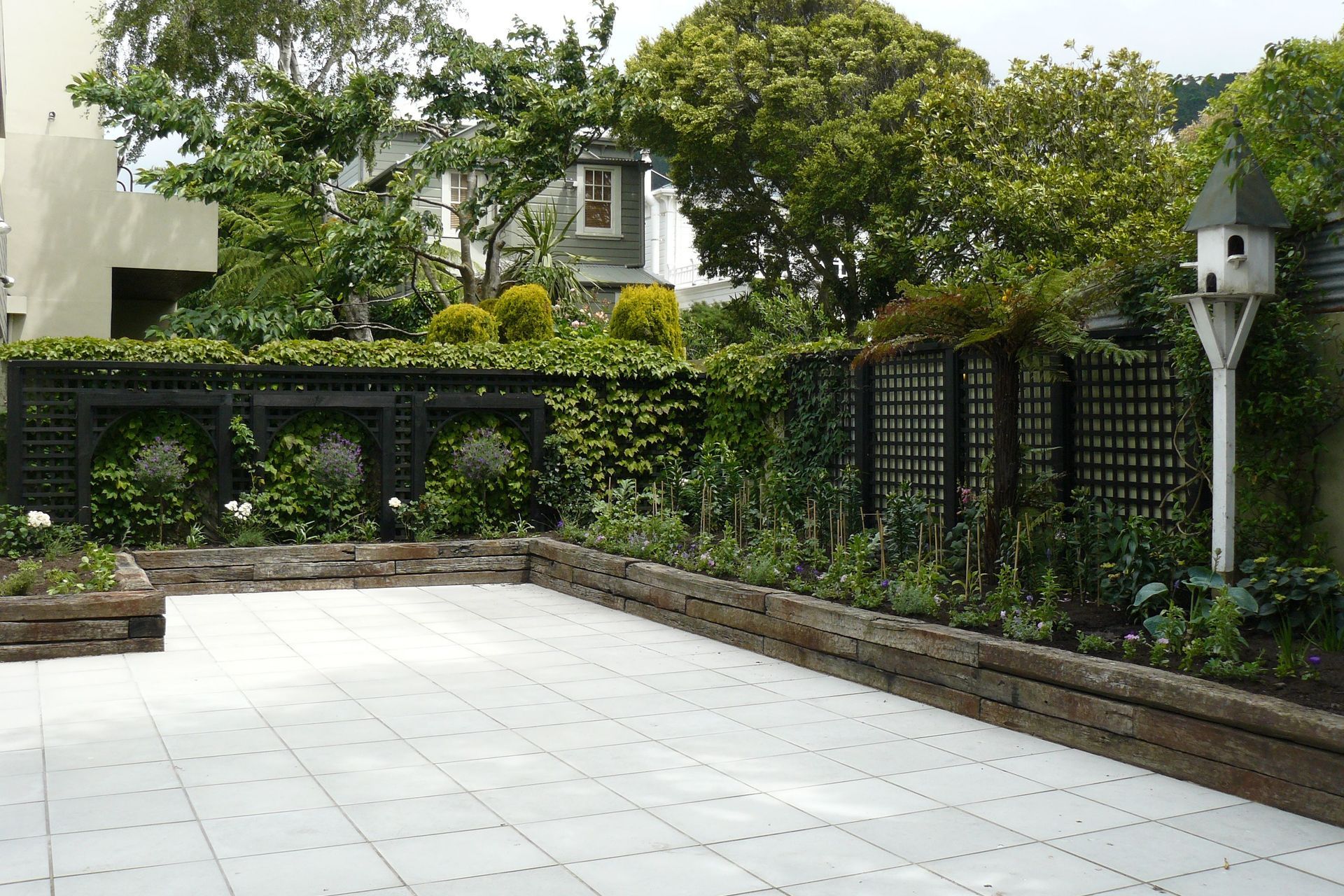 French warehouse theme,  retaining in old sleepers, timber trellising, concrete pavers and beautiful planting. Another apartment garden in Thorndon.