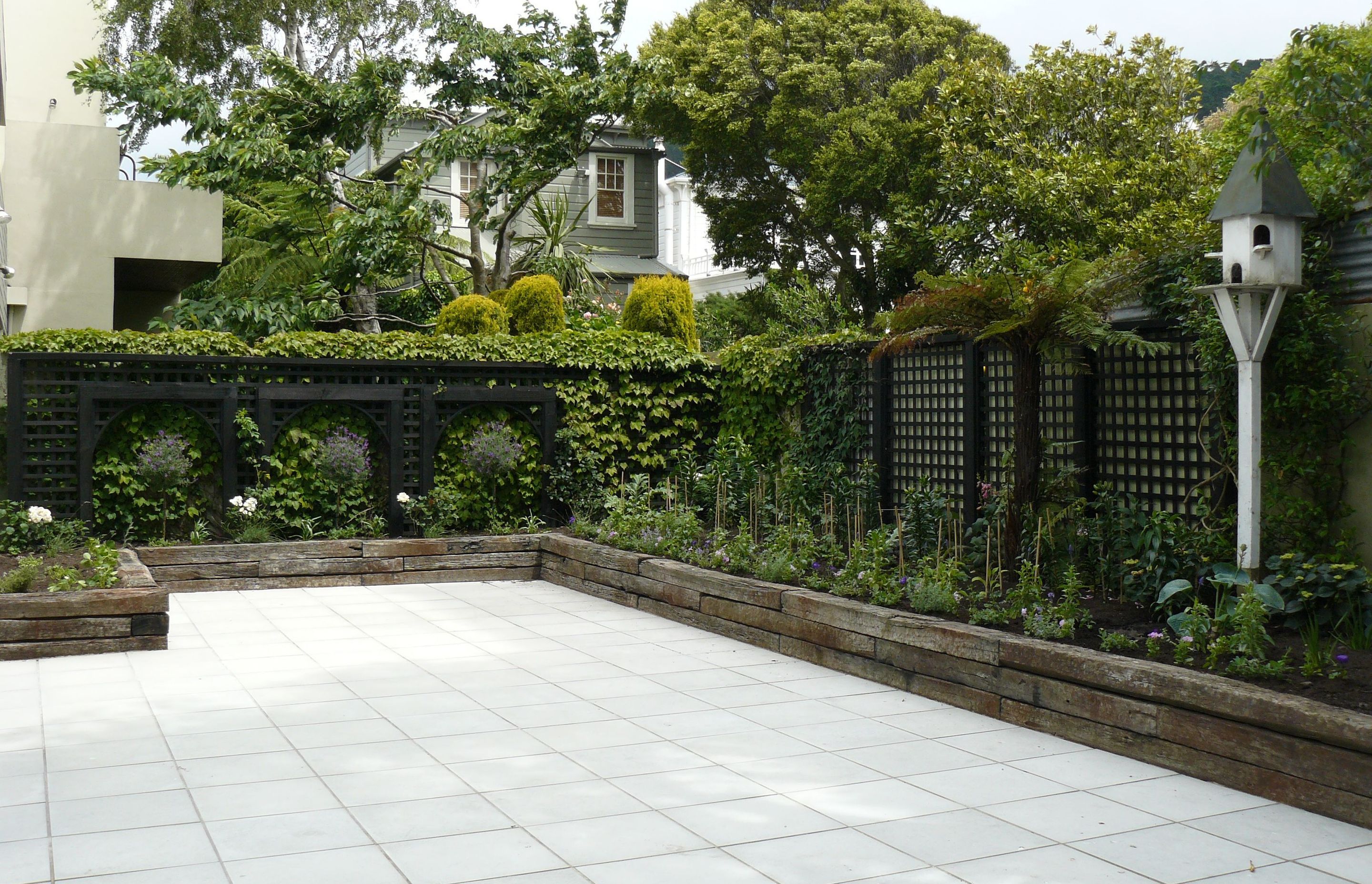 French warehouse theme,  retaining in old sleepers, timber trellising, concrete pavers and beautiful planting. Another apartment garden in Thorndon.