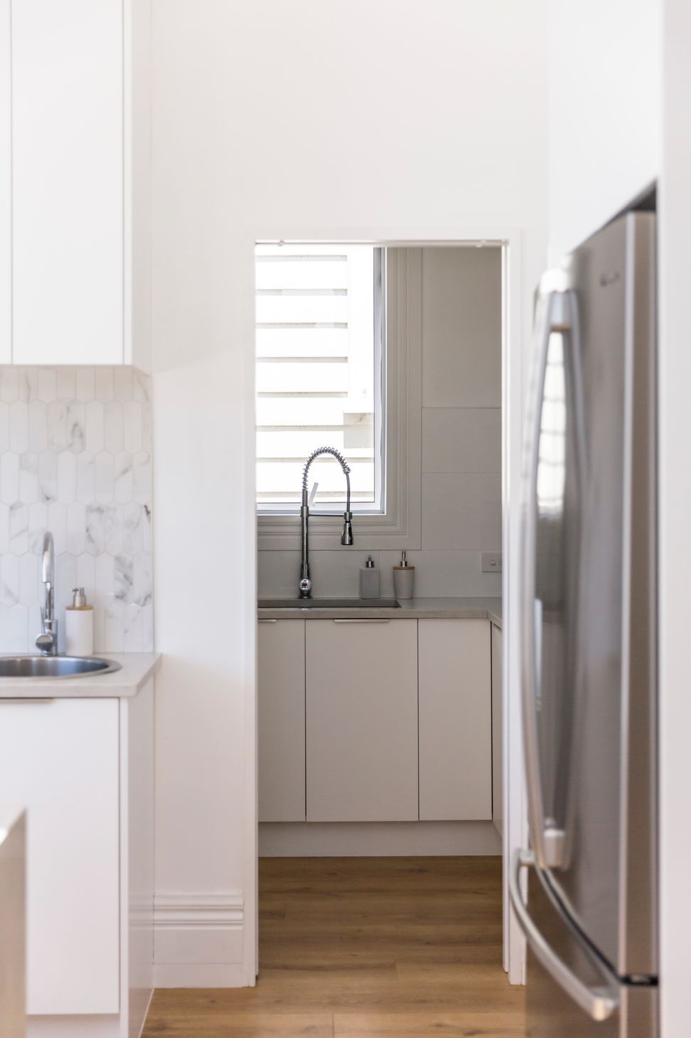 The scullery at Grey Lynn Villa — marble splashback, white cabinetry and a considered utility space tucked neatly into the new addition. Macfie Architecture.