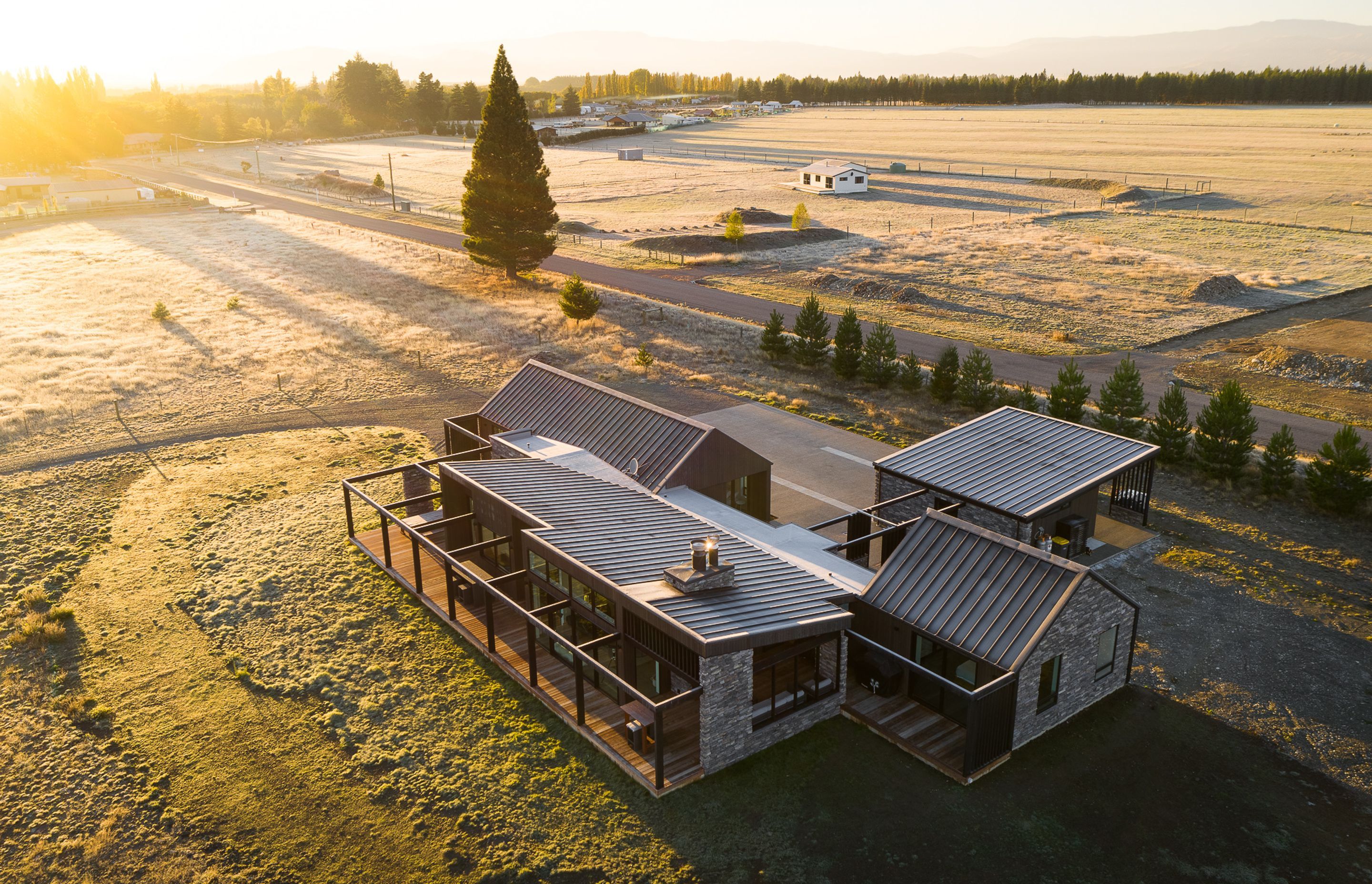 The main living, kitchen and dining spaces are located to the front and open out to the main view. Guest bedrooms, laundry and utility spaces sit behind and frame the driveway access to the rear of the house