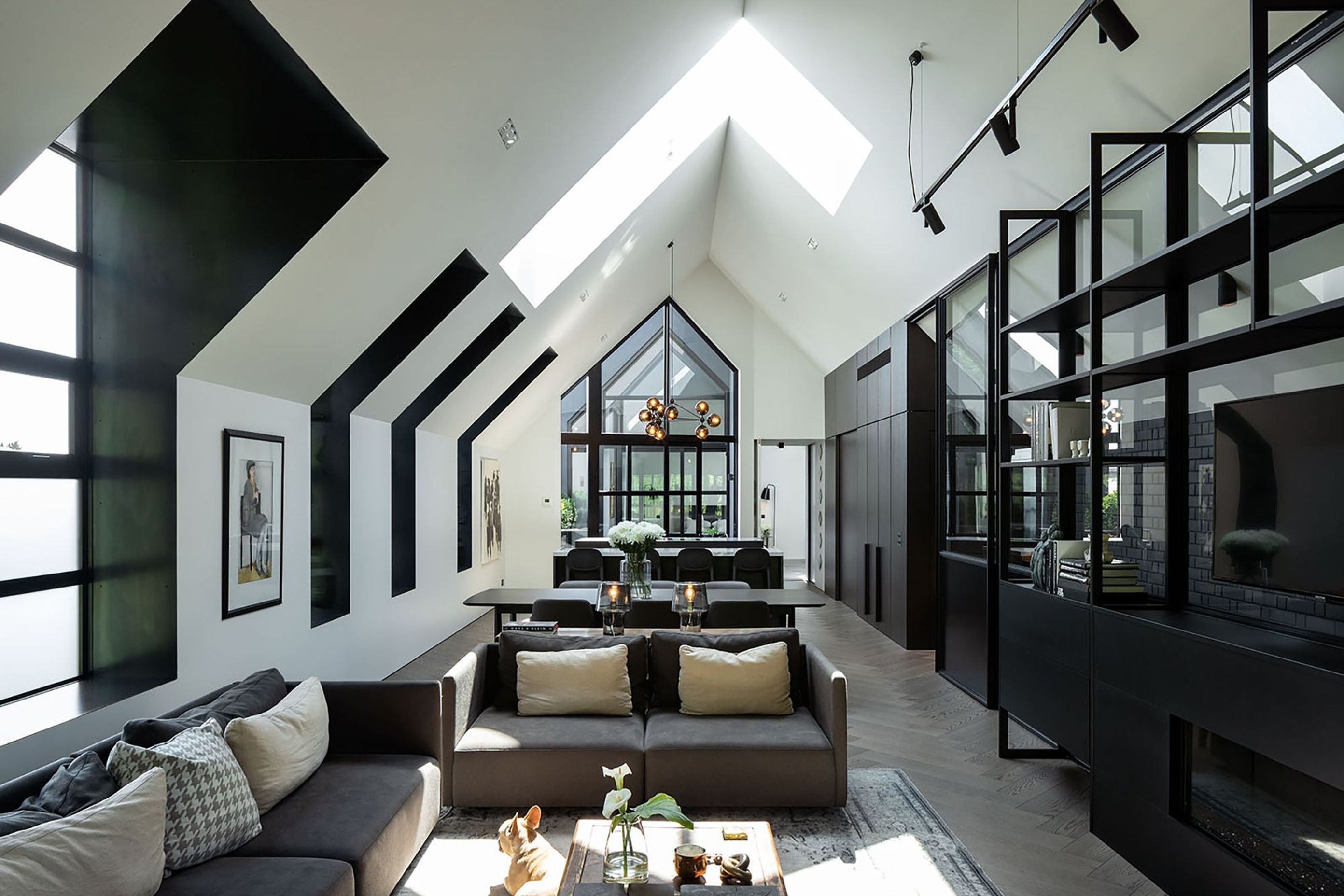 The main living area offers a heightened sense of verticality, drawing light in through a series of dormer windows and a skylight.