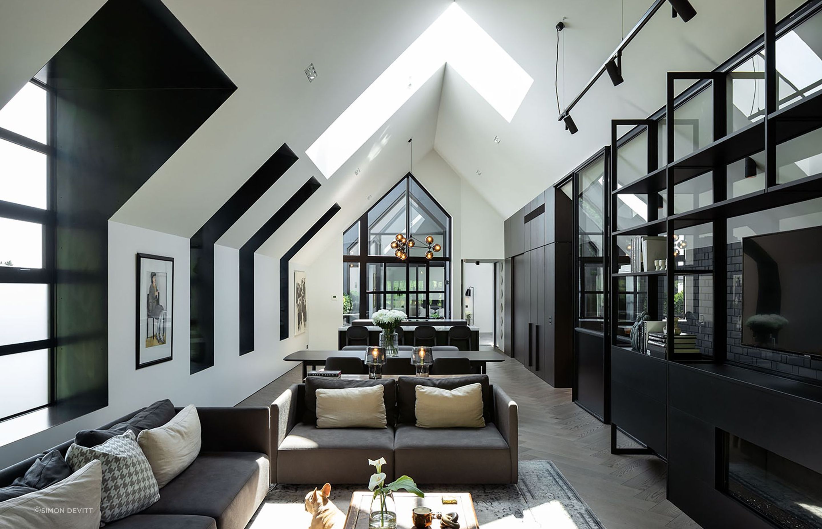 The main living area offers a heightened sense of verticality, drawing light in through a series of dormer windows and a skylight.
