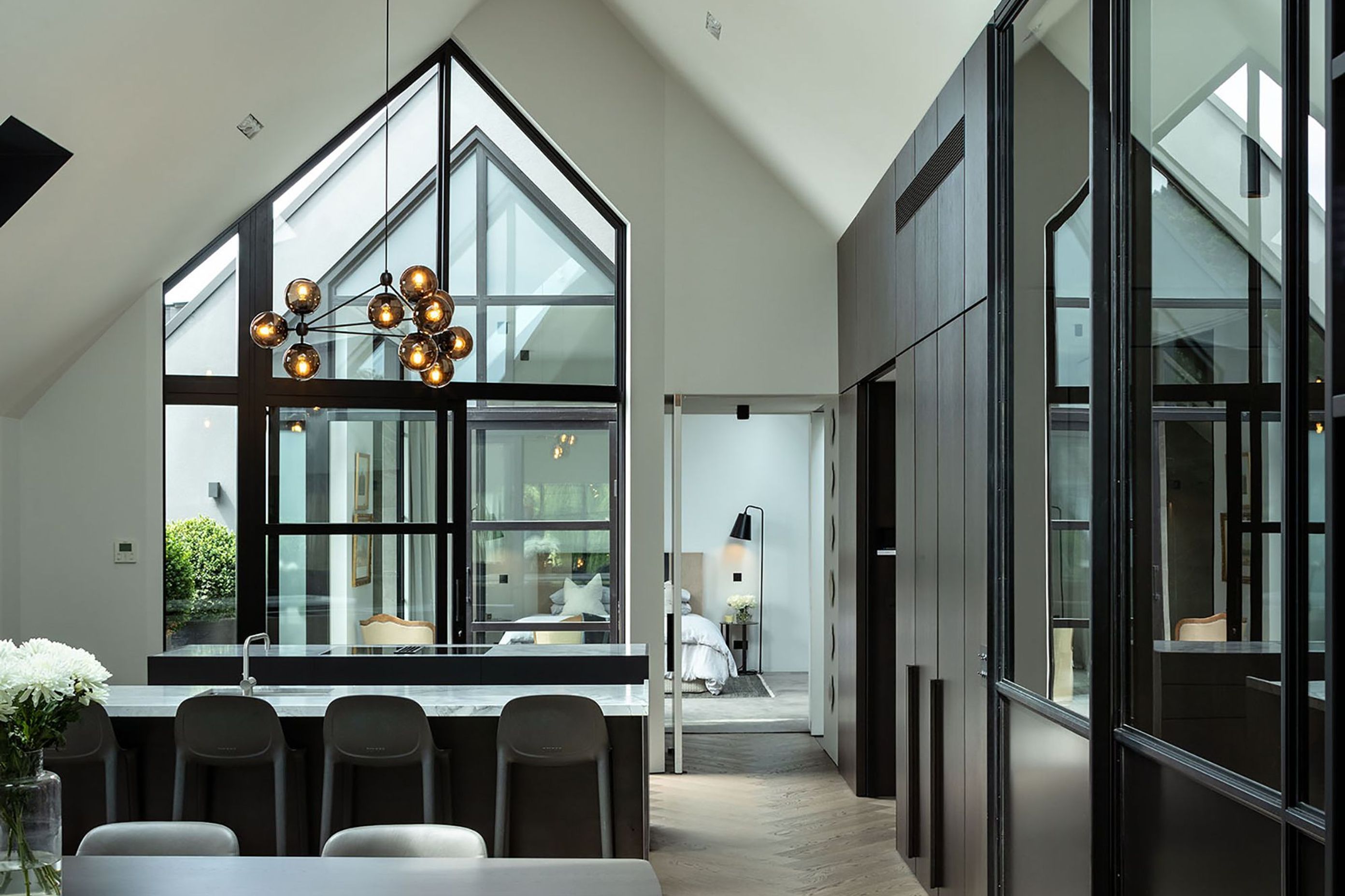 The  minimalist kitchen is a celebration of smooth and textural surfaces that play with the light drawn in from two sides and above.the double-height gabled window.
