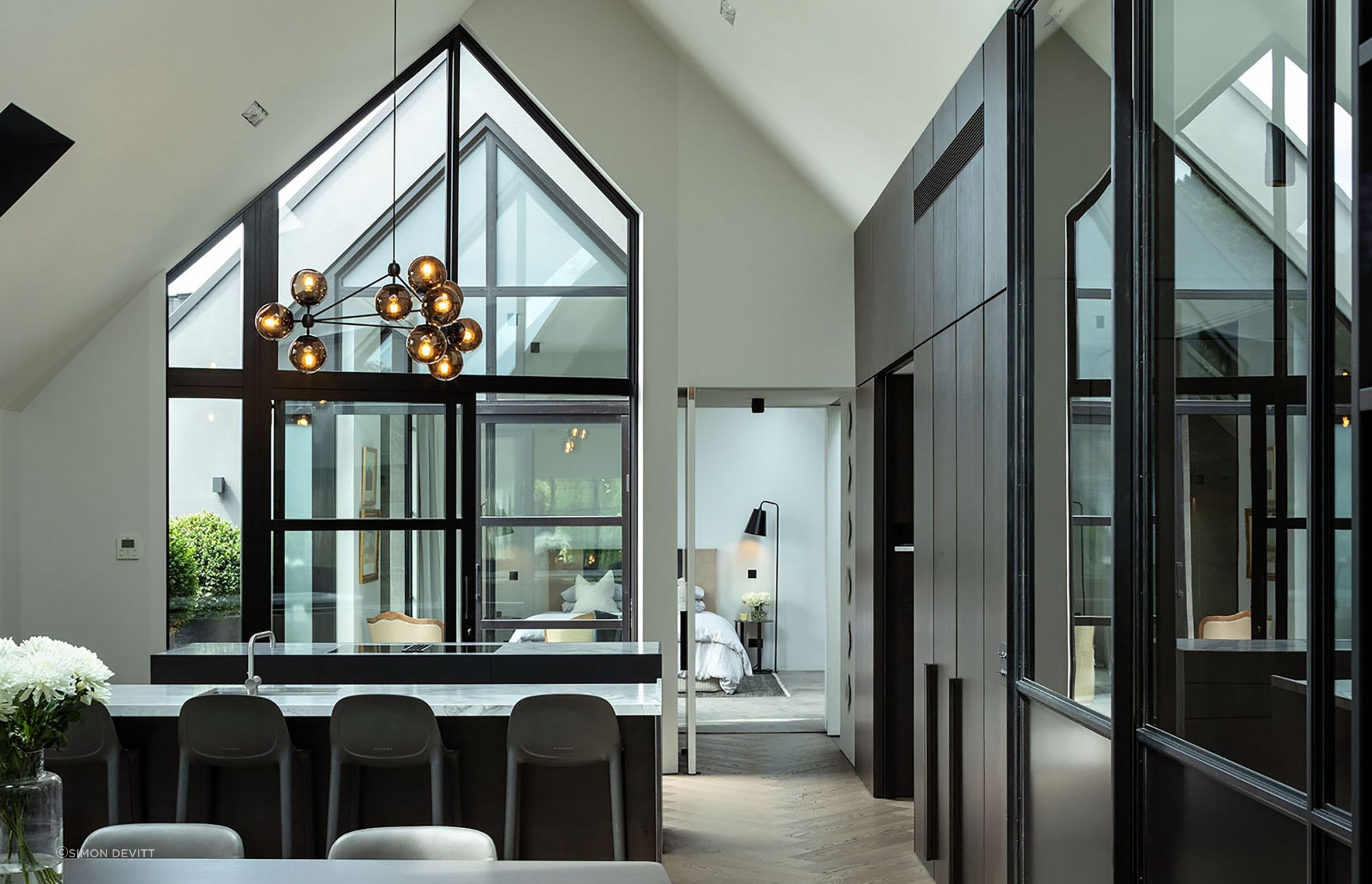 The minimalist kitchen is a celebration of smooth and textural surfaces that play with the light drawn in from two sides and above.the double-height gabled window.
