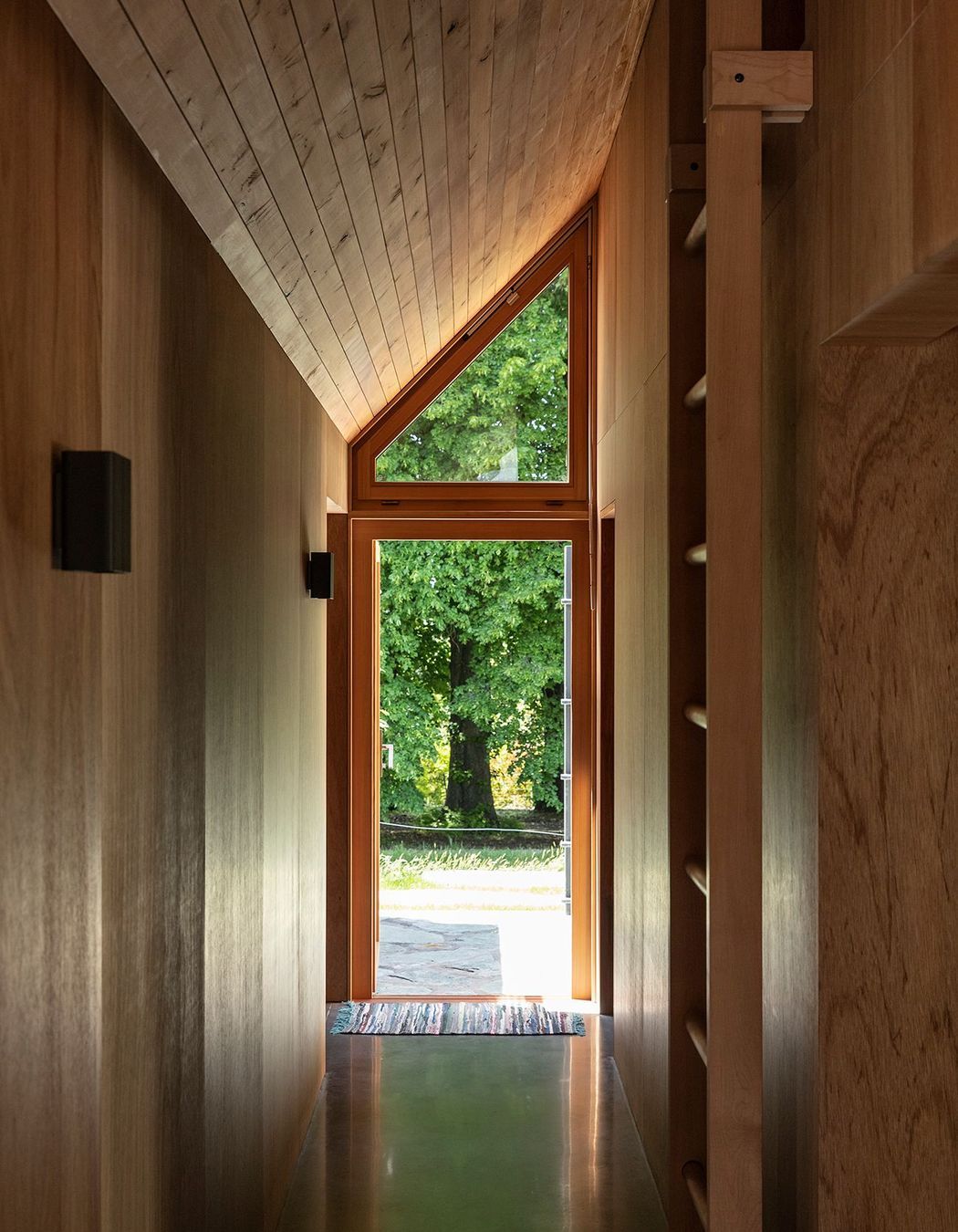 The corridor lines up with a large oak tree, accentuated by the steeply angled roof.
