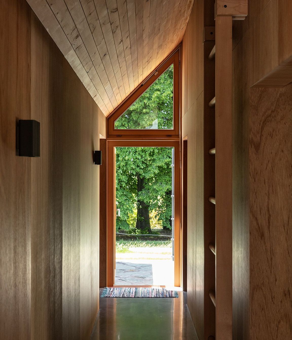 The corridor lines up with a large oak tree, accentuated by the steeply angled roof.
