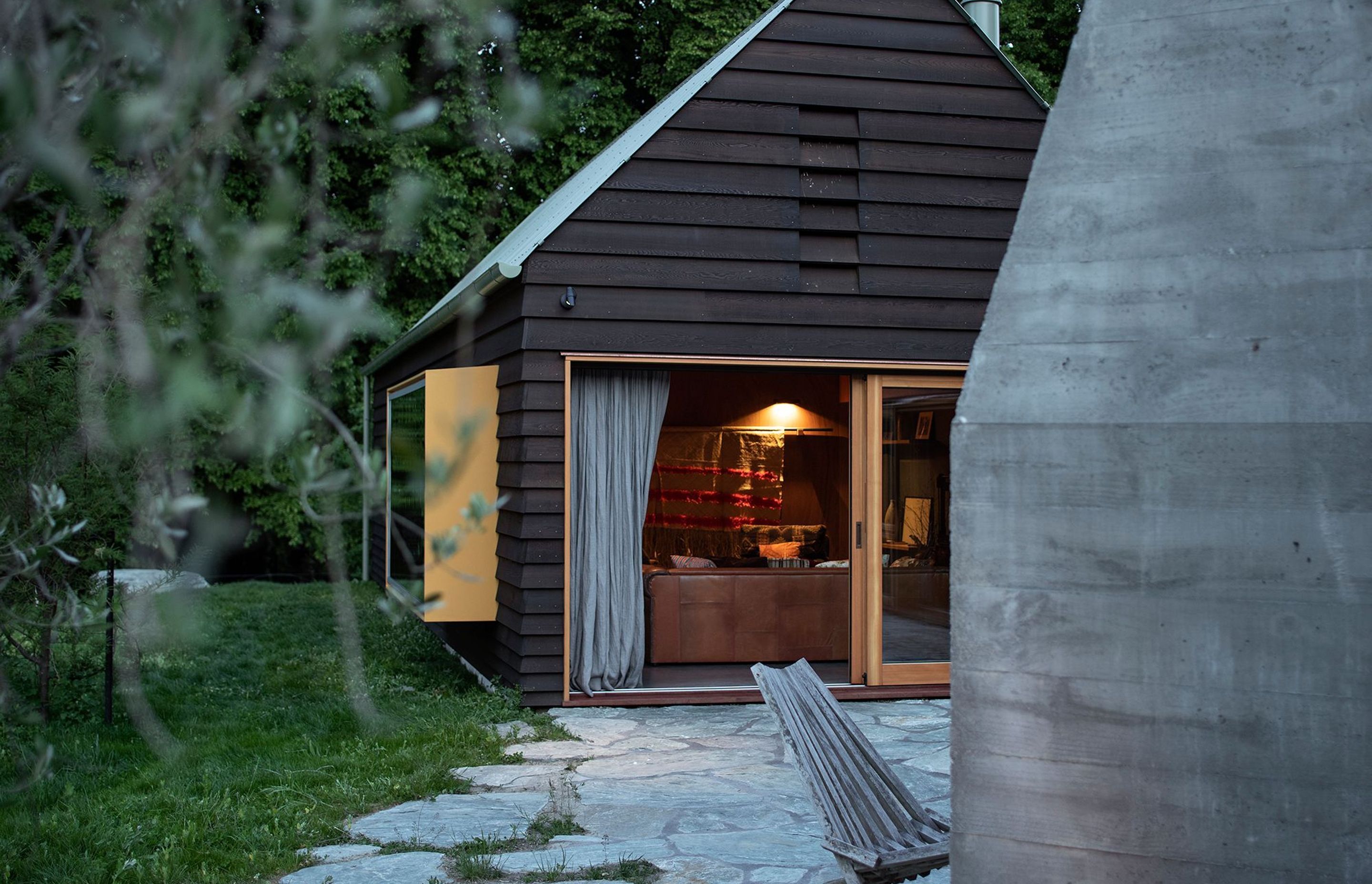 The living space has a yellow pop-out reading window that overlooks the lawn. The schist pavers have undefined edges that seem to dissolve into the lawn.