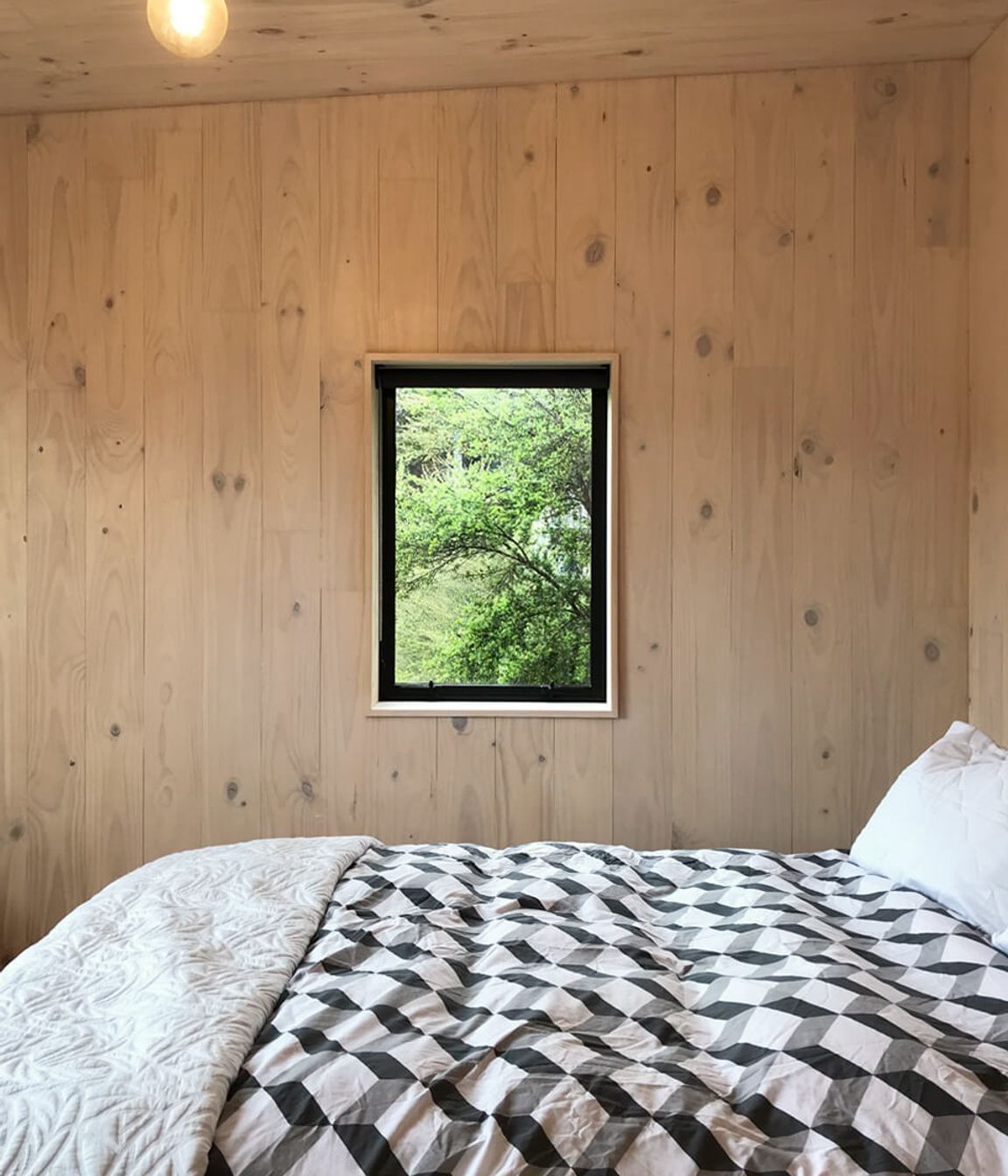 A picture windows in the upstairs  bedroom frame a view of the bush.