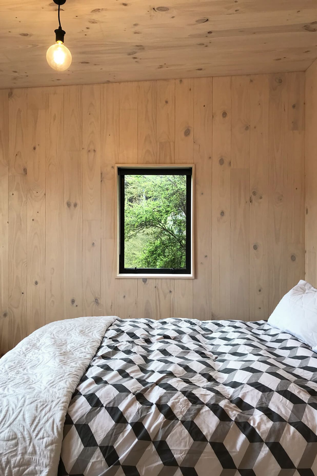 A picture windows in the upstairs bedroom frame a view of the bush.