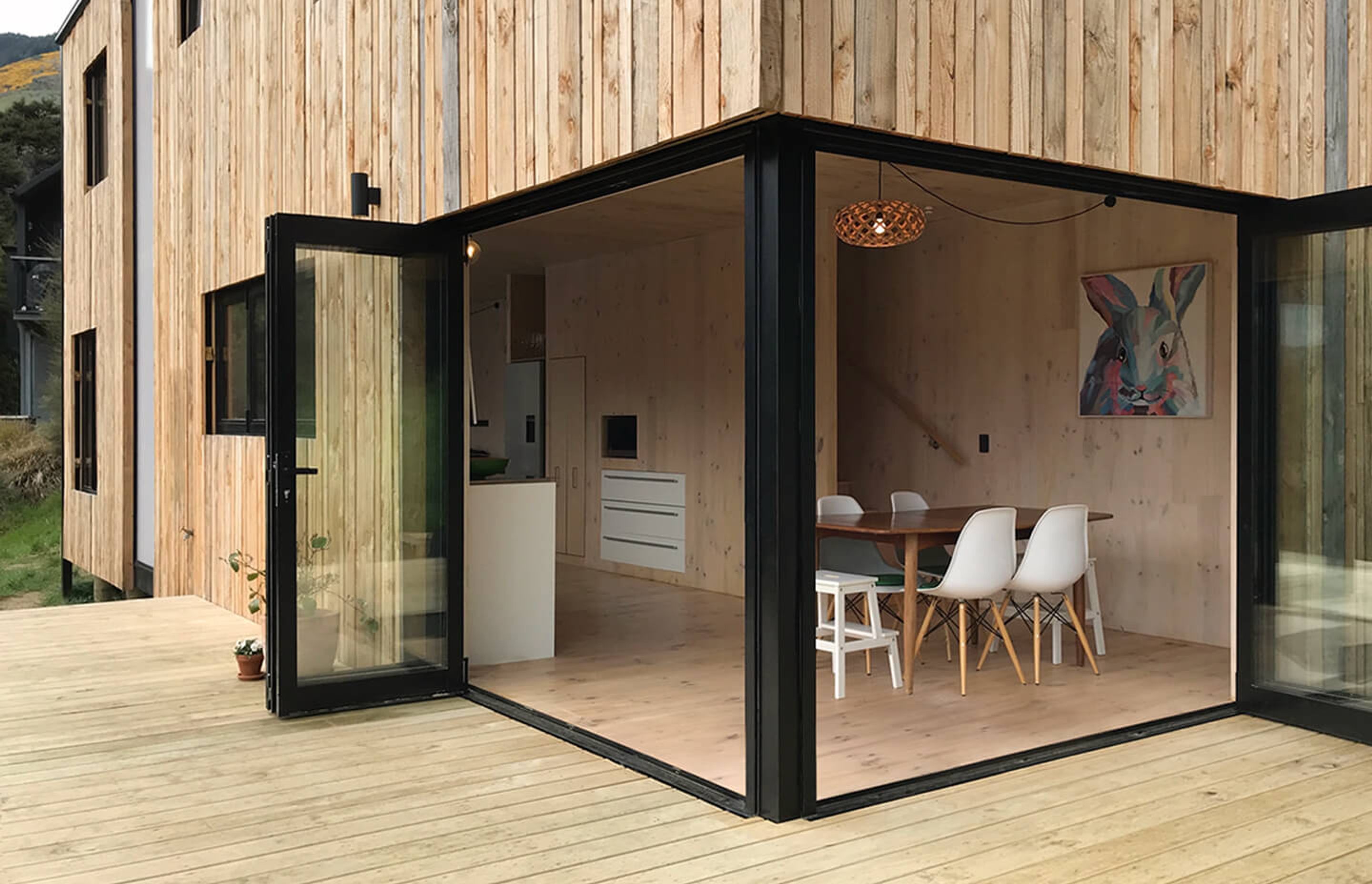 The dining area opens up on two sides by a deck that overlooks the valley. The cross-laminated timber interior marries neatly with the timber exterior.