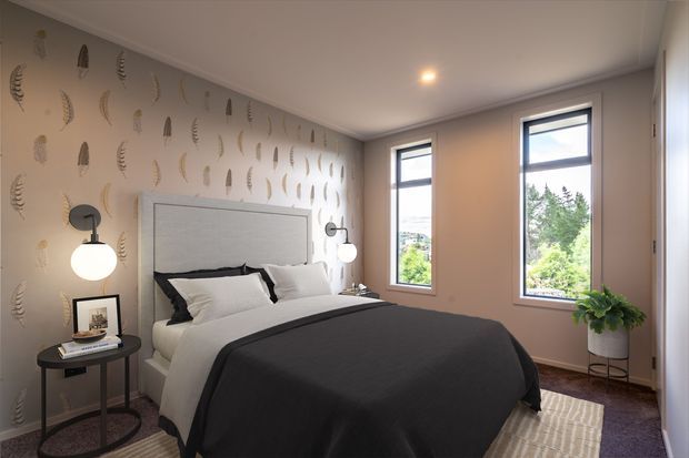 A refined bedroom with a large upholstered bed, white bedding and a dark charcoal throw. The room features botanical-patterned wallpaper, slim black-framed windows, wall-mounted globe sconces, a small round bedside table, and a potted plant. Soft neutral finishes and natural daylight create a calm, contemporary atmosphere.