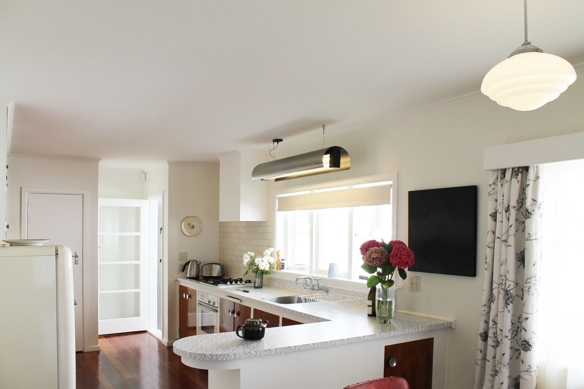 Streamlining the original layout to incorporate an integrated oven, cooktop and dishwasher into the old cabinets by pulling them forward allowed more bench top space in this large kitchen. This design achieved the blend of modern function with retro elega