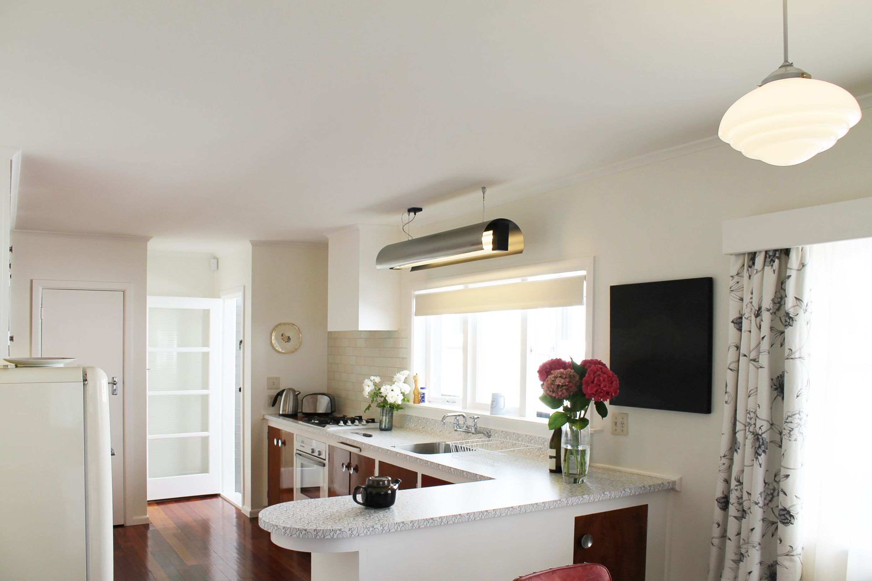 Streamlining the original layout to incorporate an integrated oven, cooktop and dishwasher into the old cabinets by pulling them forward allowed more bench top space in this large kitchen. This design achieved the blend of modern function with retro elega