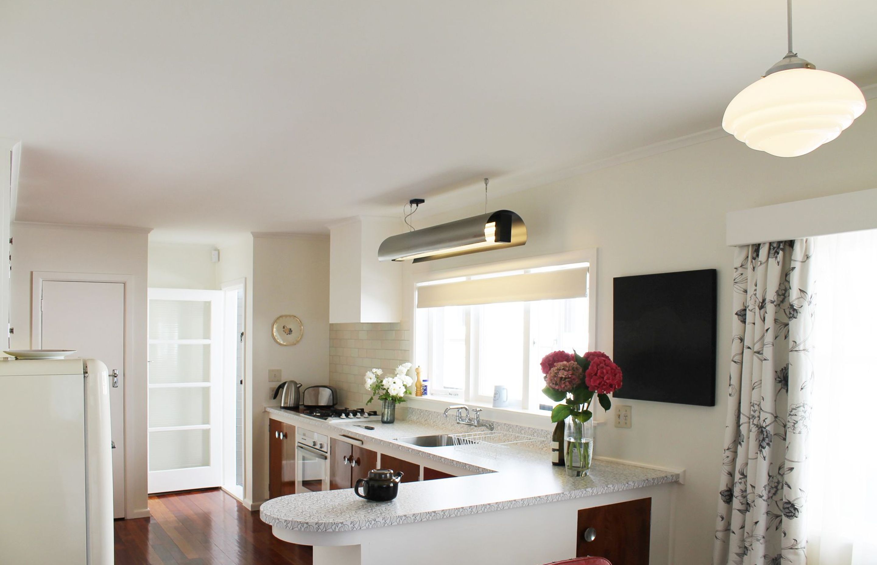 Streamlining the original layout to incorporate an integrated oven, cooktop and dishwasher into the old cabinets by pulling them forward allowed more bench top space in this large kitchen. This design achieved the blend of modern function with retro elega