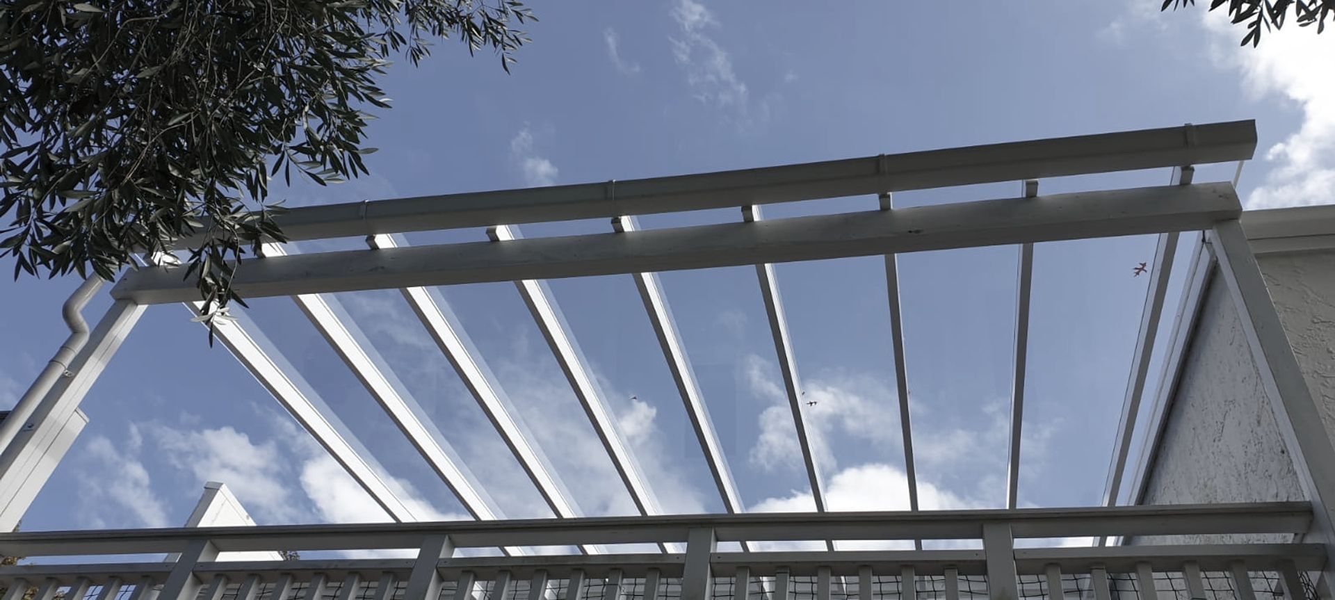 Upper level deck roof using painted white timber frame with clear panels.