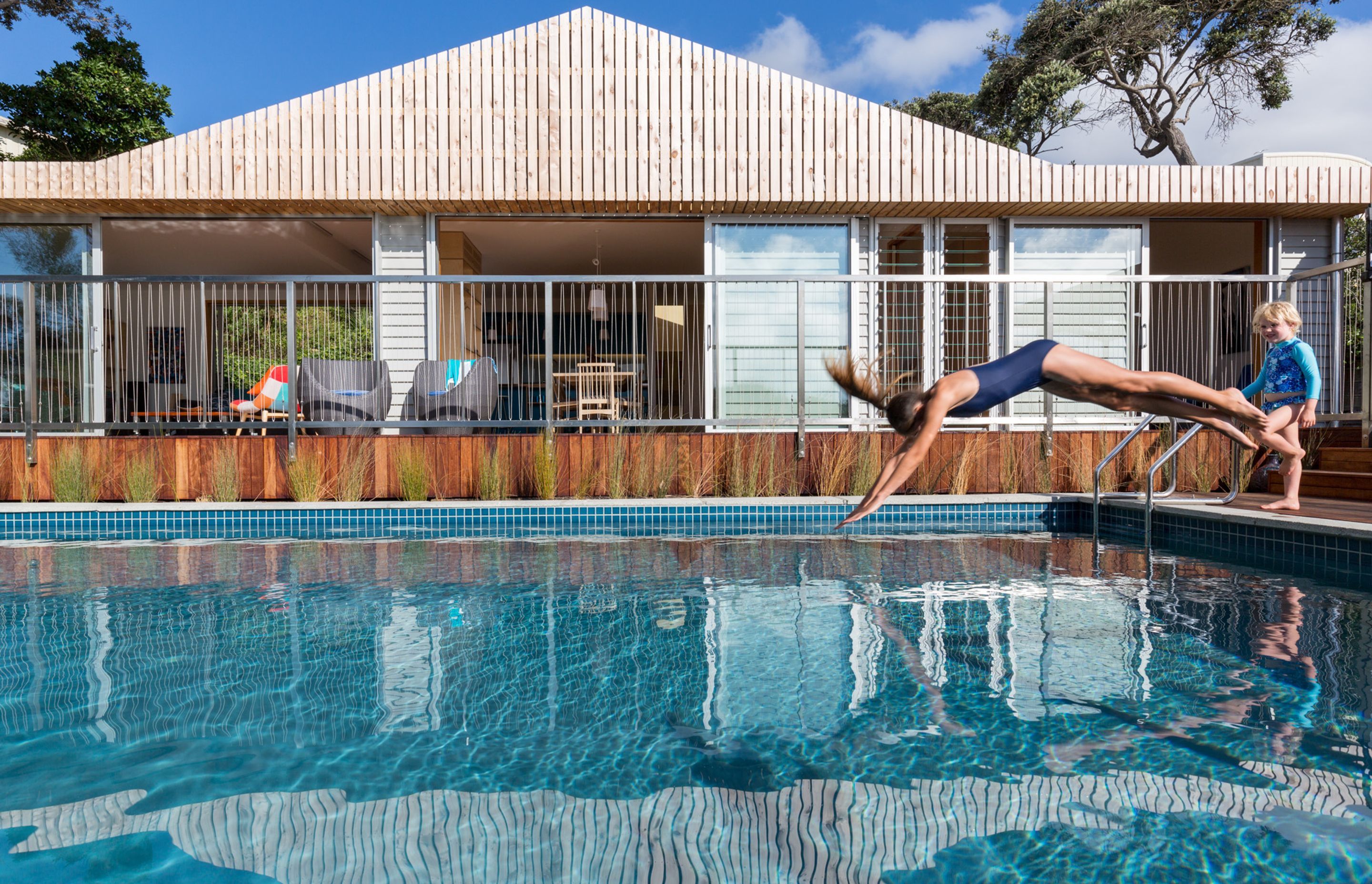 The swimming pool, added to the property in the 1950s has been fully refurbished. Bevelled weatherboards reference the original cottage while slatted macrocarpa elements add new definition and help mitigate excess solar gain.