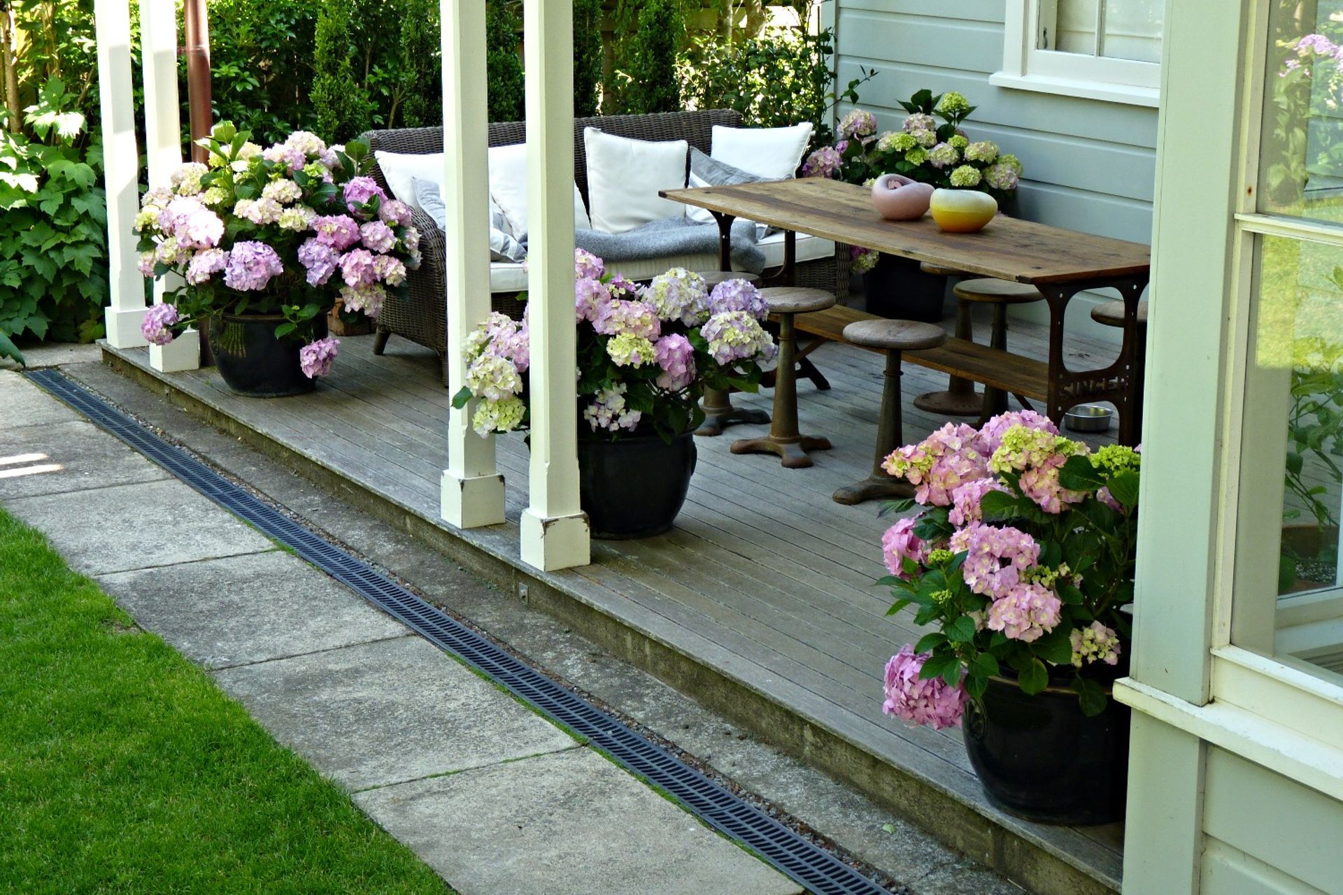 Modern Charm - super stylish outdoor living area on the large veranda. We relaid pavers to create a path / lawn edge, added lawn drainage, and decorated with pots.