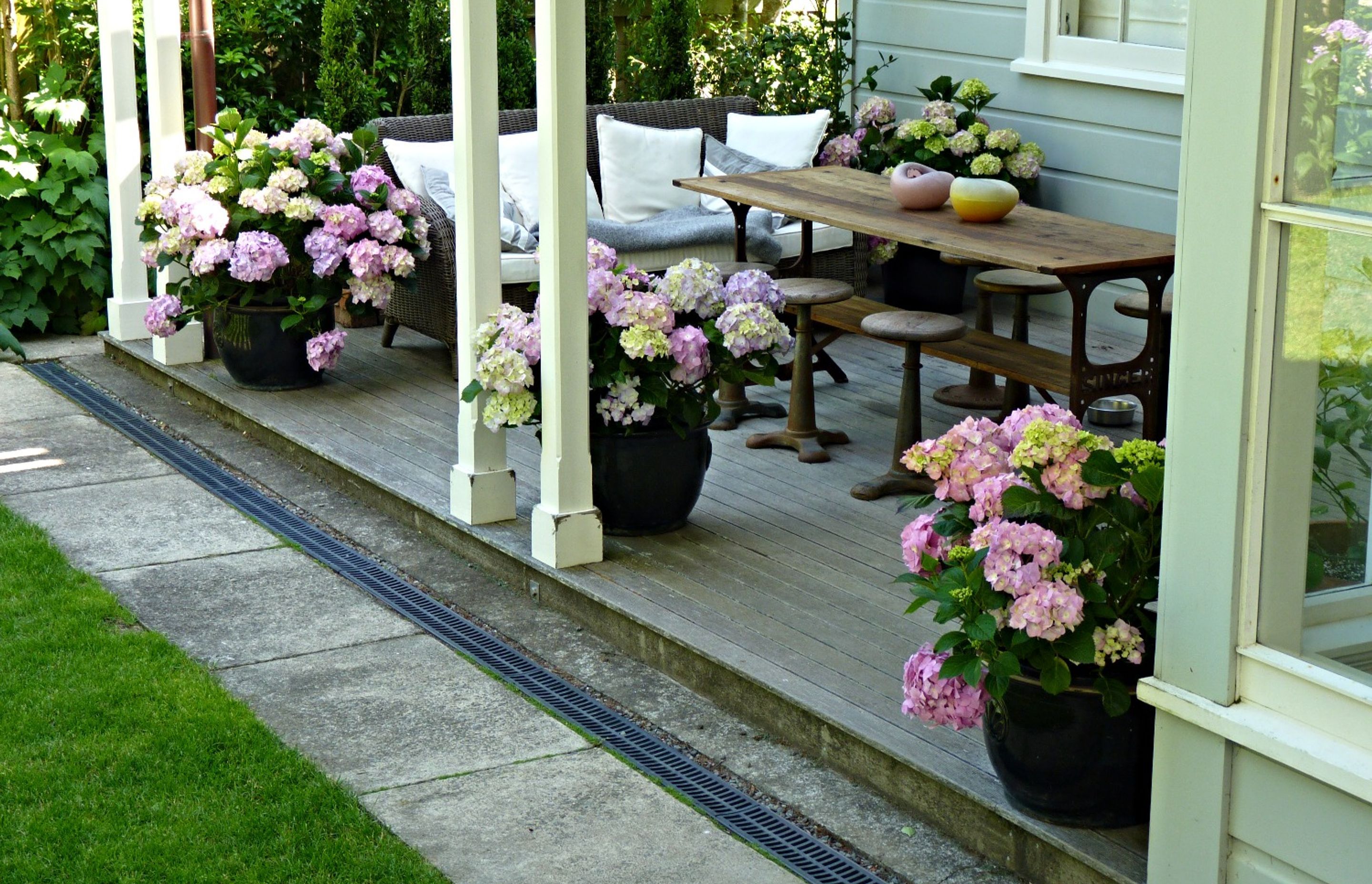 Modern Charm - super stylish outdoor living area on the large veranda. We relaid pavers to create a path / lawn edge, added lawn drainage, and decorated with pots.
