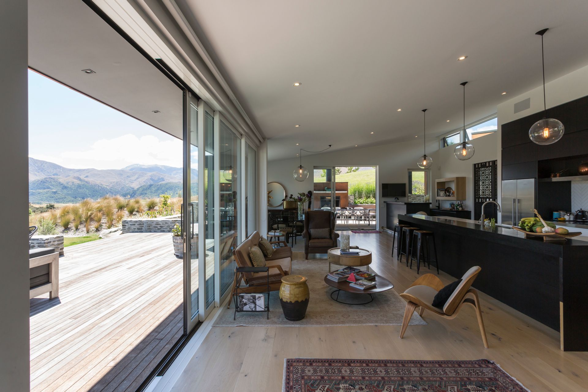 A casual living area leads onto a large deck, which is accessed via full-width stacking sliders.