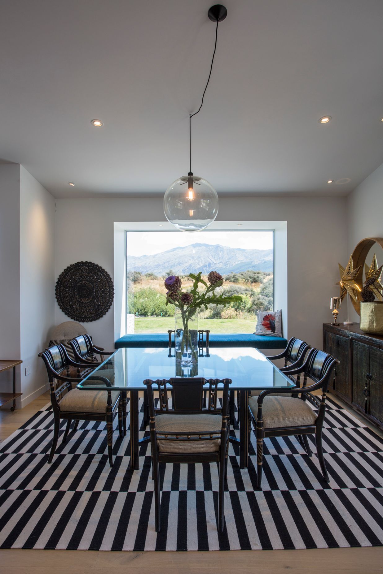 A large picture window frames the formal dining area creating a vignette of the view beyond.