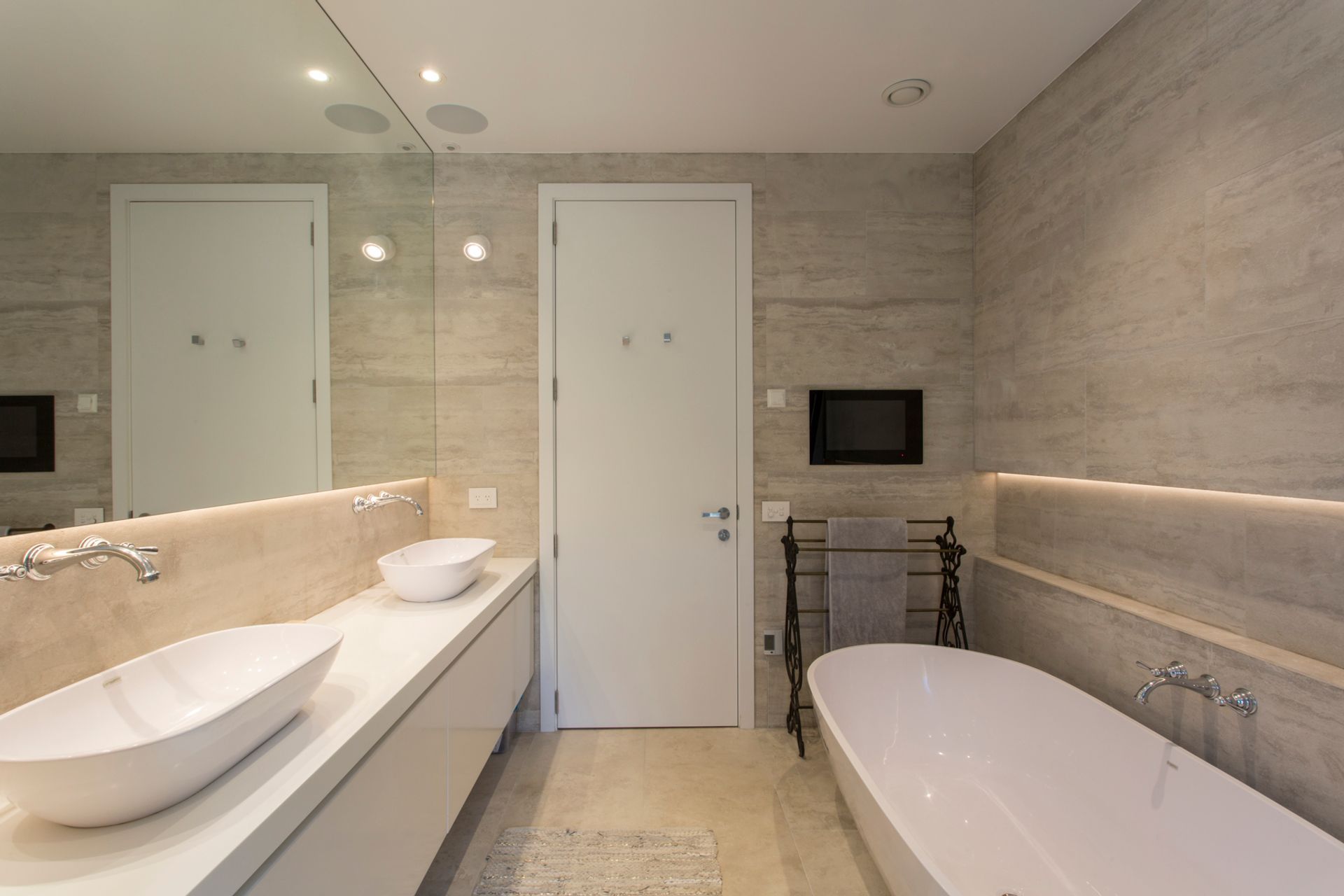 Subtle earthy tones and textures define this ensuite bathroom while the classic-style tapware contrasts the sleek nature of the bath and basins.