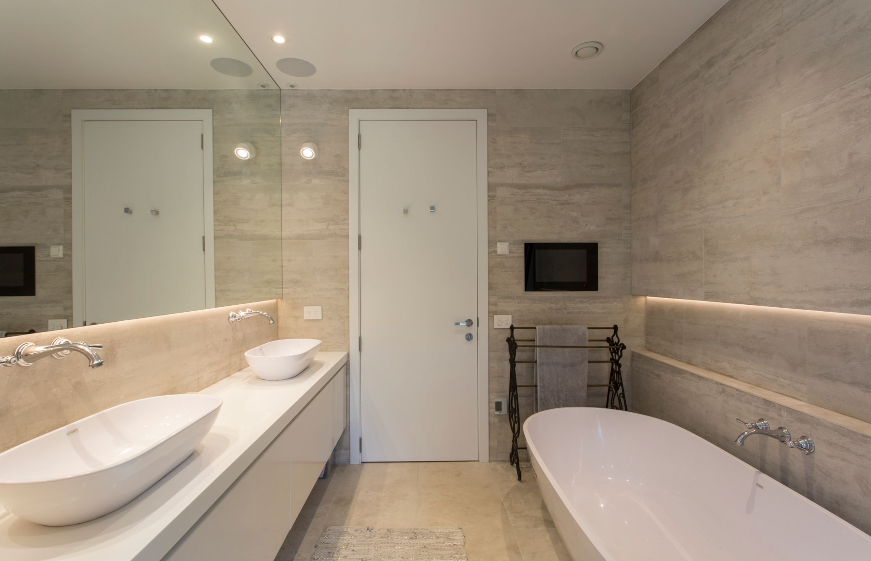 Subtle earthy tones and textures define this ensuite bathroom while the classic-style tapware contrasts the sleek nature of the bath and basins.