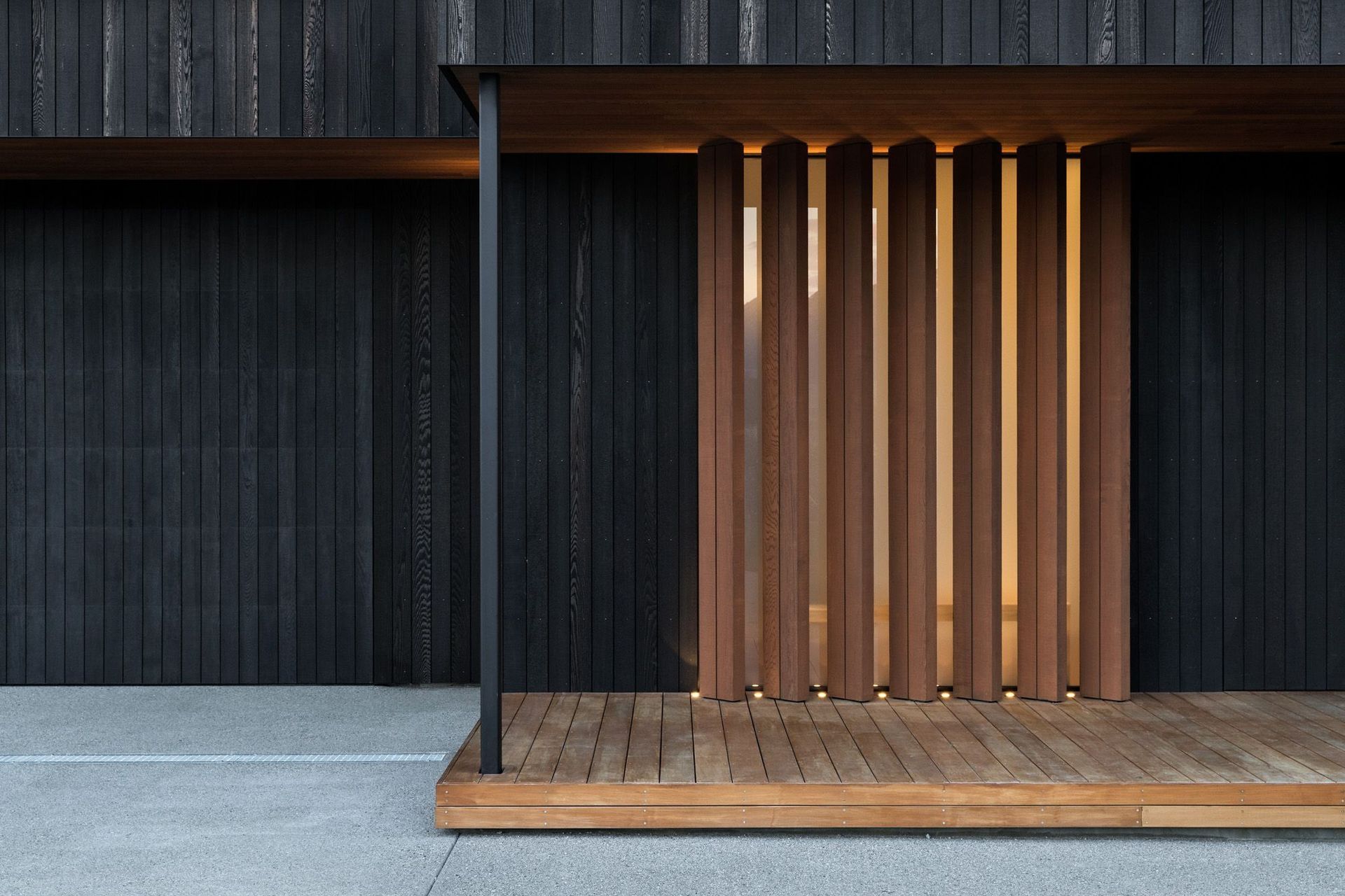 The main entrance features warm timber vertical louvres, where you enter into light-filled spaces that are arranged around an interior courtyard and a covered outdoor room. 