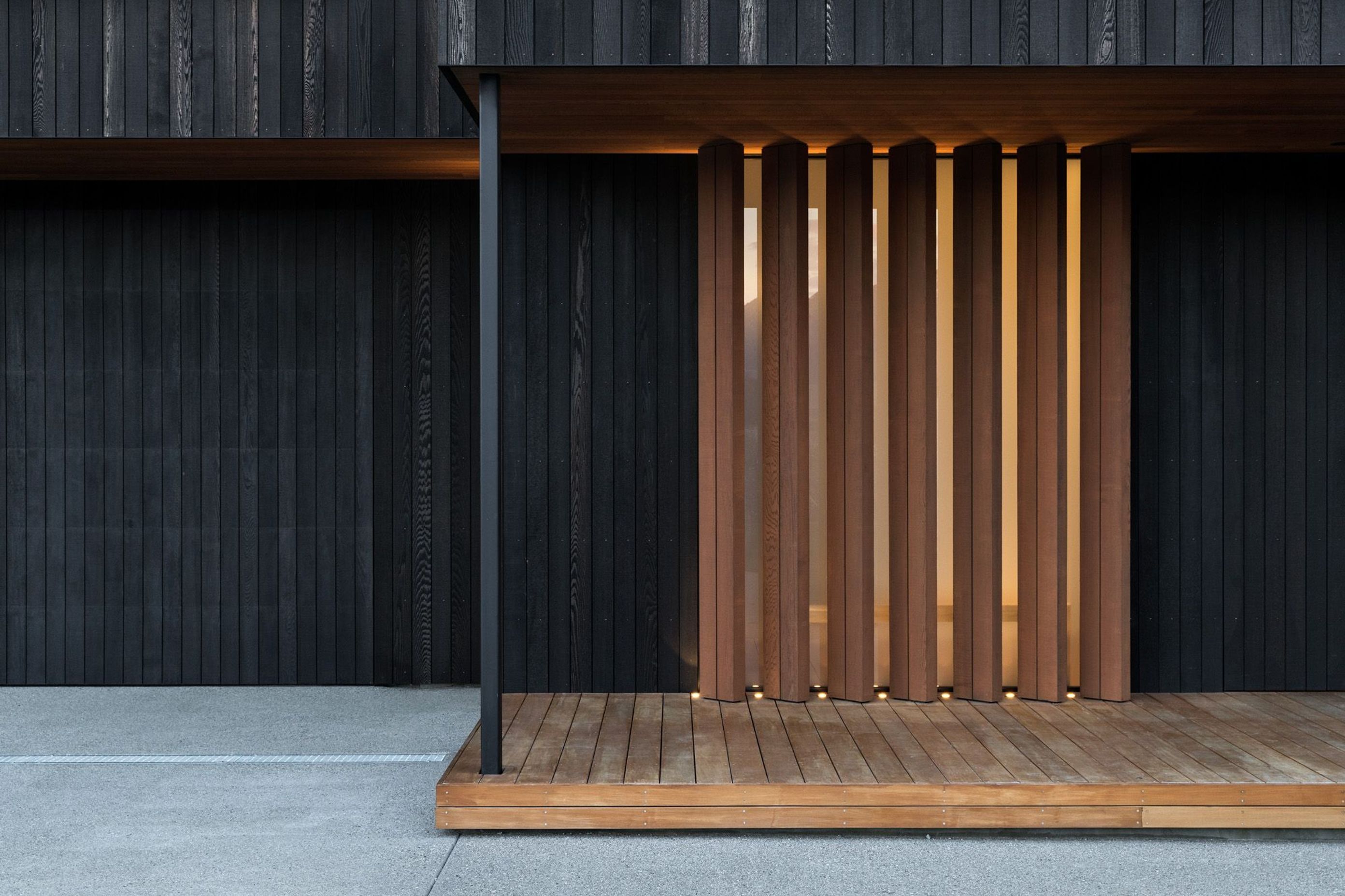 The main entrance features warm timber vertical louvres, where you enter into light-filled spaces that are arranged around an interior courtyard and a covered outdoor room. 