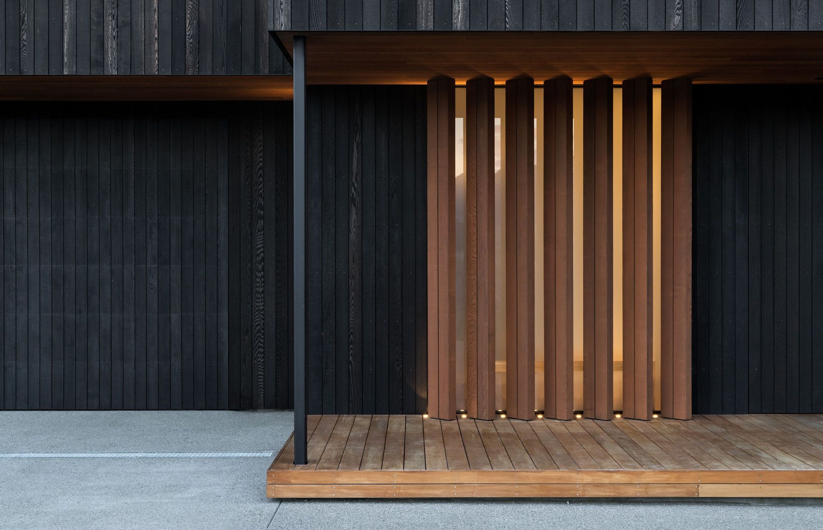 The main entrance features warm timber vertical louvres, where you enter into light-filled spaces that are arranged around an interior courtyard and a covered outdoor room. 