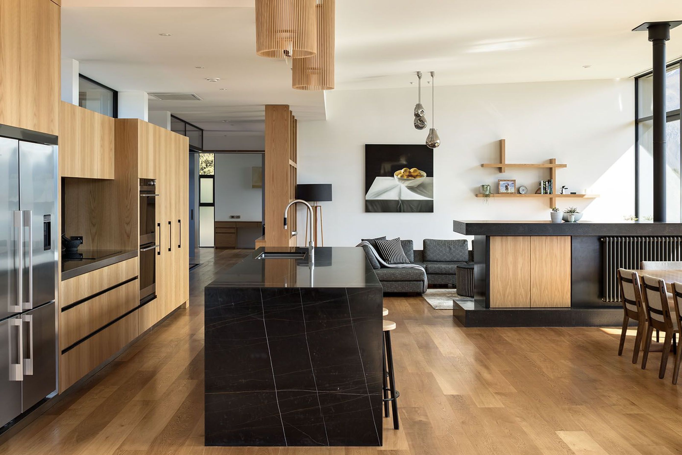 In the open-plan kitchen/dining/living space, a low custom-made room divide hosts a centrally-heated radiator, a television and storage.