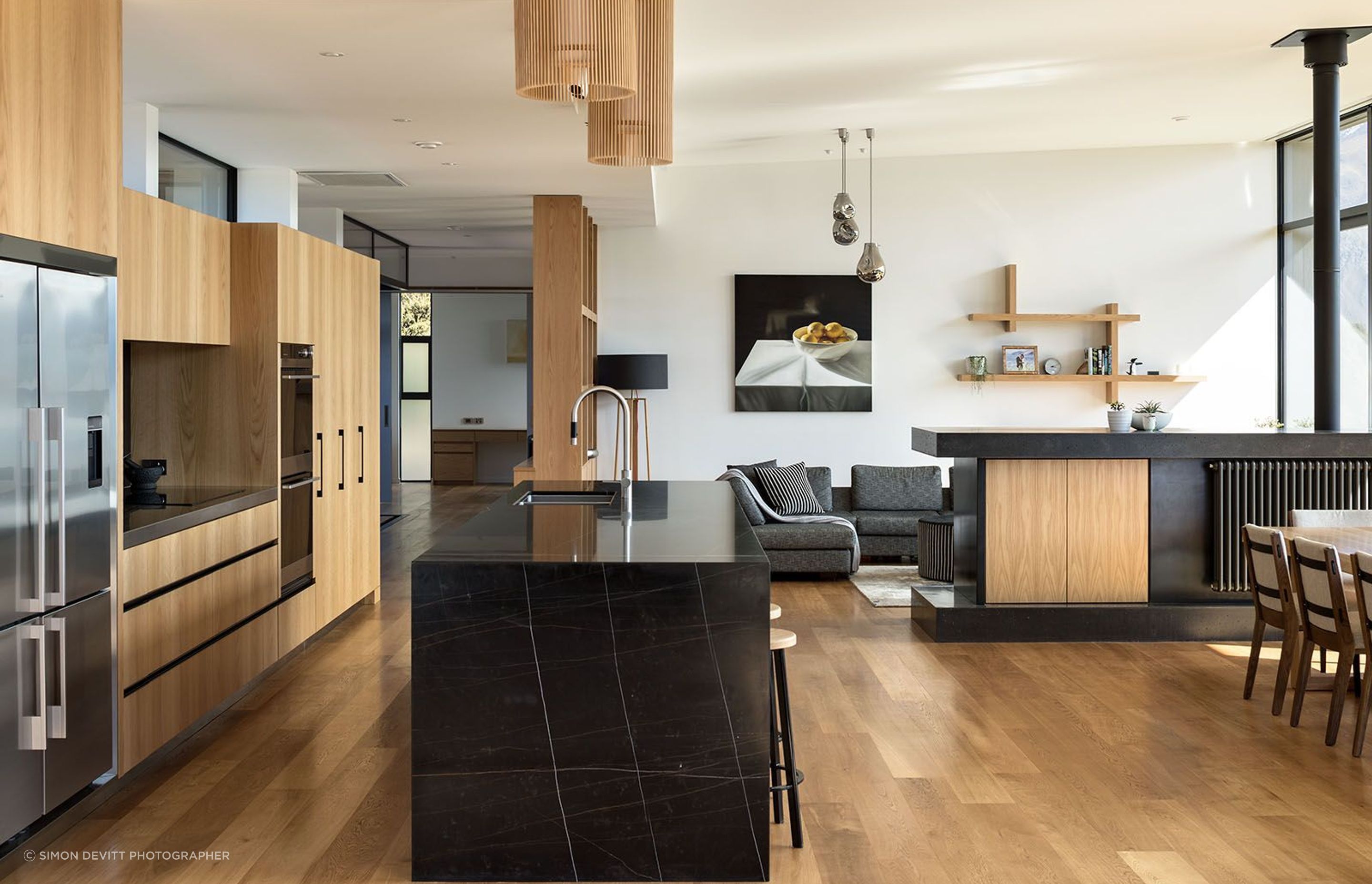 In the open-plan kitchen/dining/living space, a low custom-made room divide hosts a centrally-heated radiator, a television and storage.