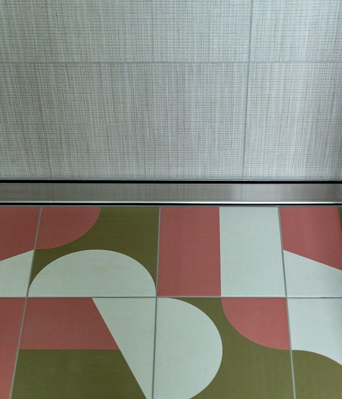 Graphic geometric tiling on the bathroom floor complements the linen-look wall tiles