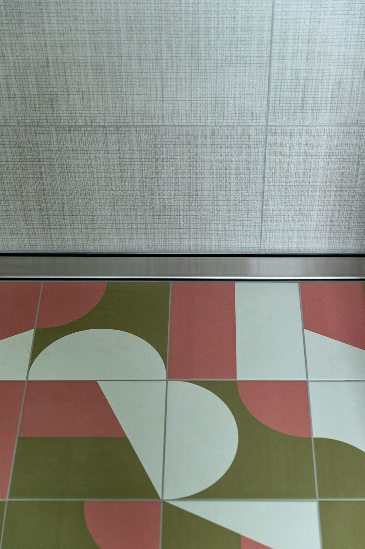 Graphic geometric tiling on the bathroom floor complements the linen-look wall tiles