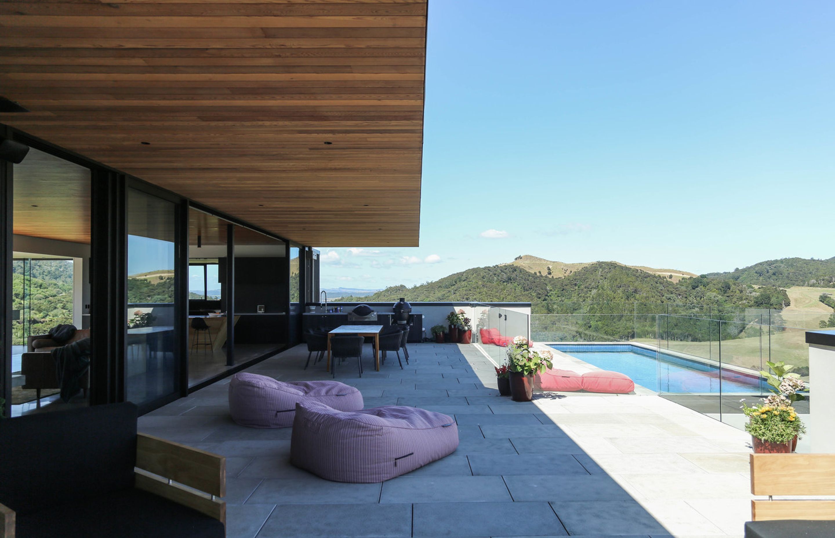 A big overhanging timber soffit protects the outdoor entertaining area, which includes a barbeque and dining area and swimming pool, from virtually all-day sun.