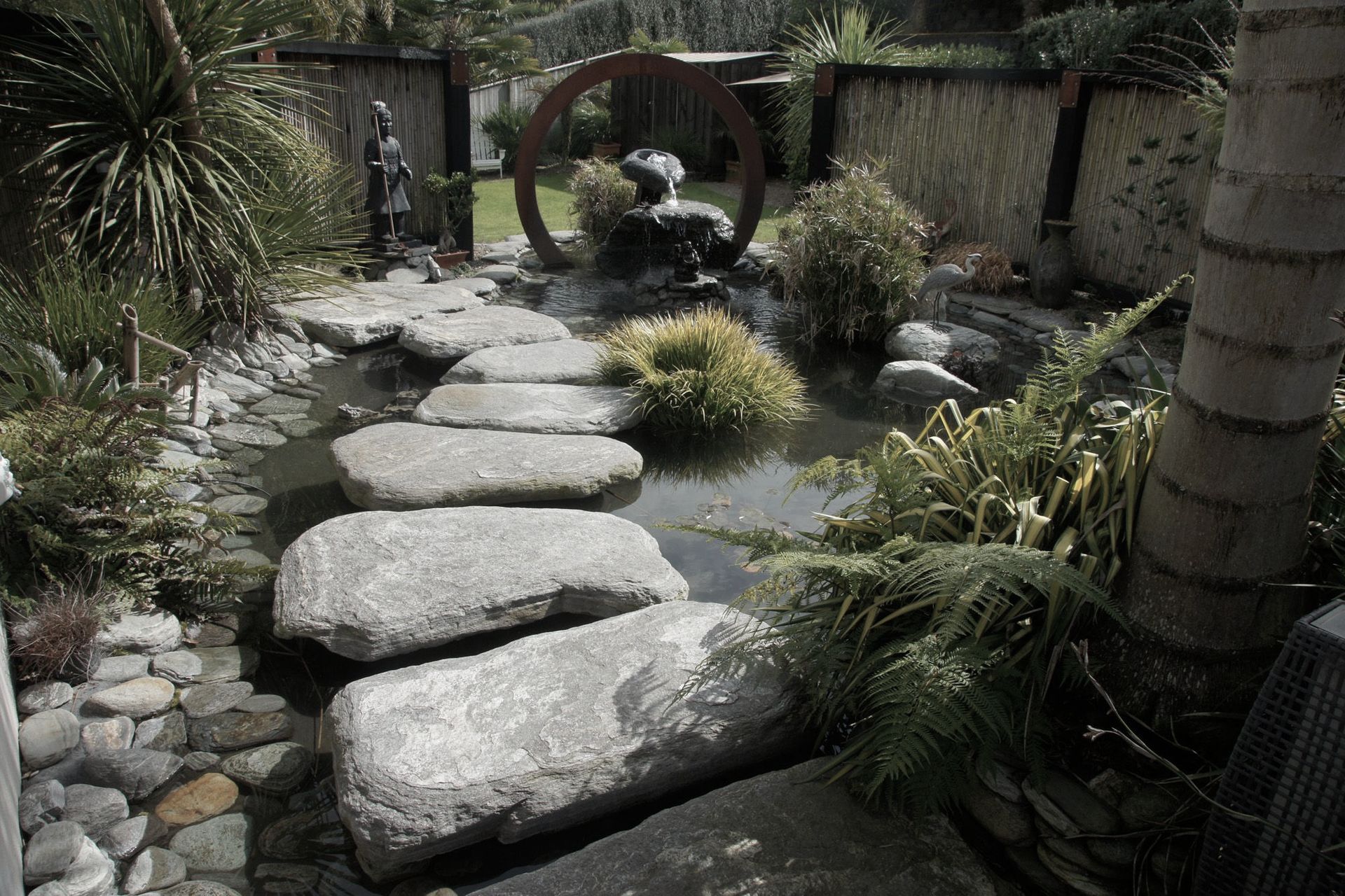 Corten steel circle features as a back drop to this natural style pond incorporating clients personal artifacts