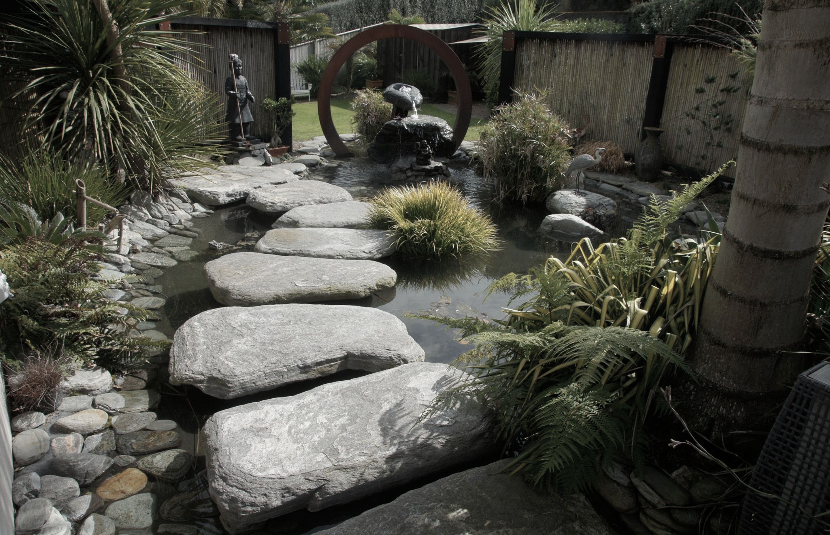 Corten steel circle features as a back drop to this natural style pond incorporating clients personal artifacts