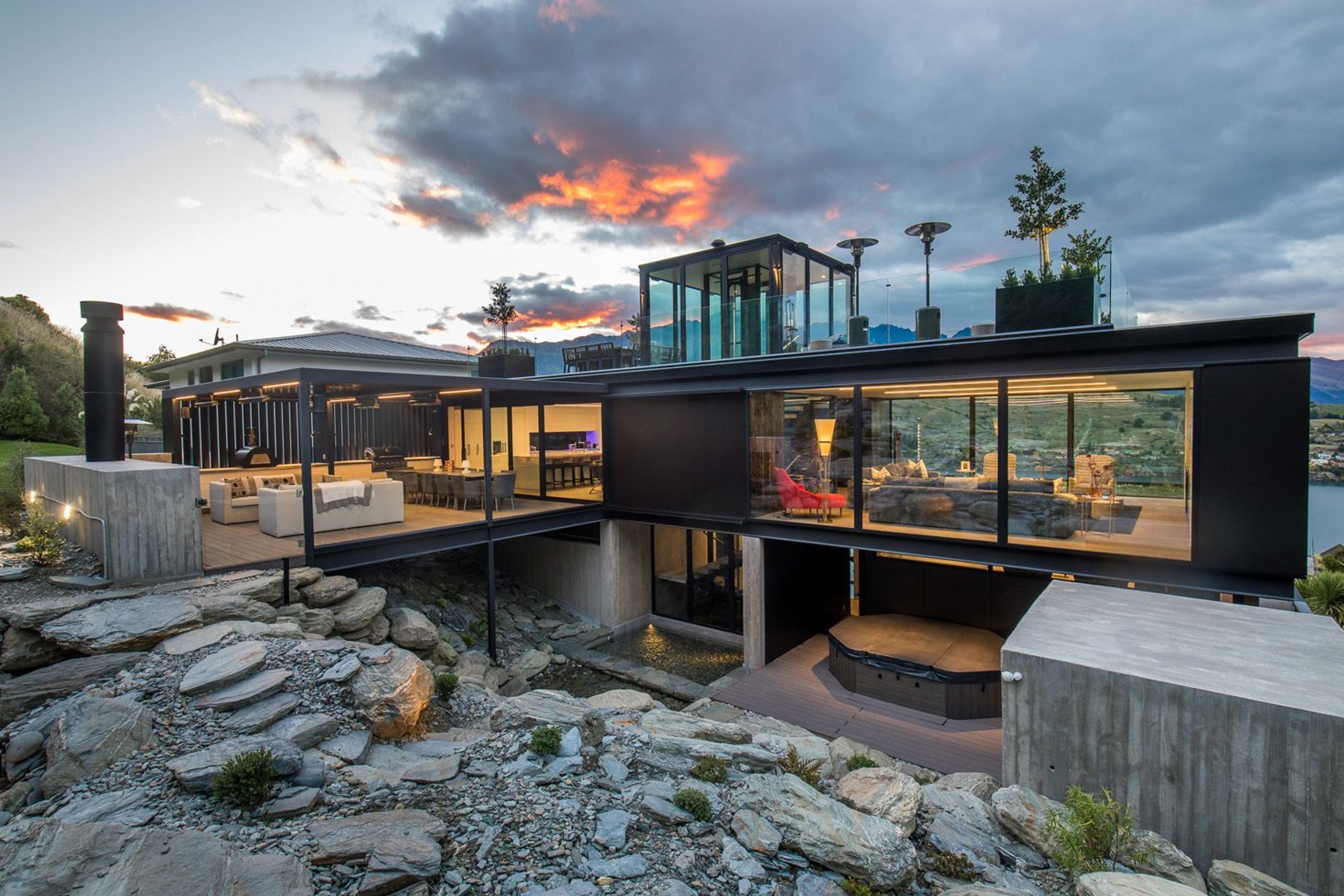 A rock garden at the rear has been excavated to create space for a spa and sauna area, and a reflection pool, which are overlooked by the outdoor room above.