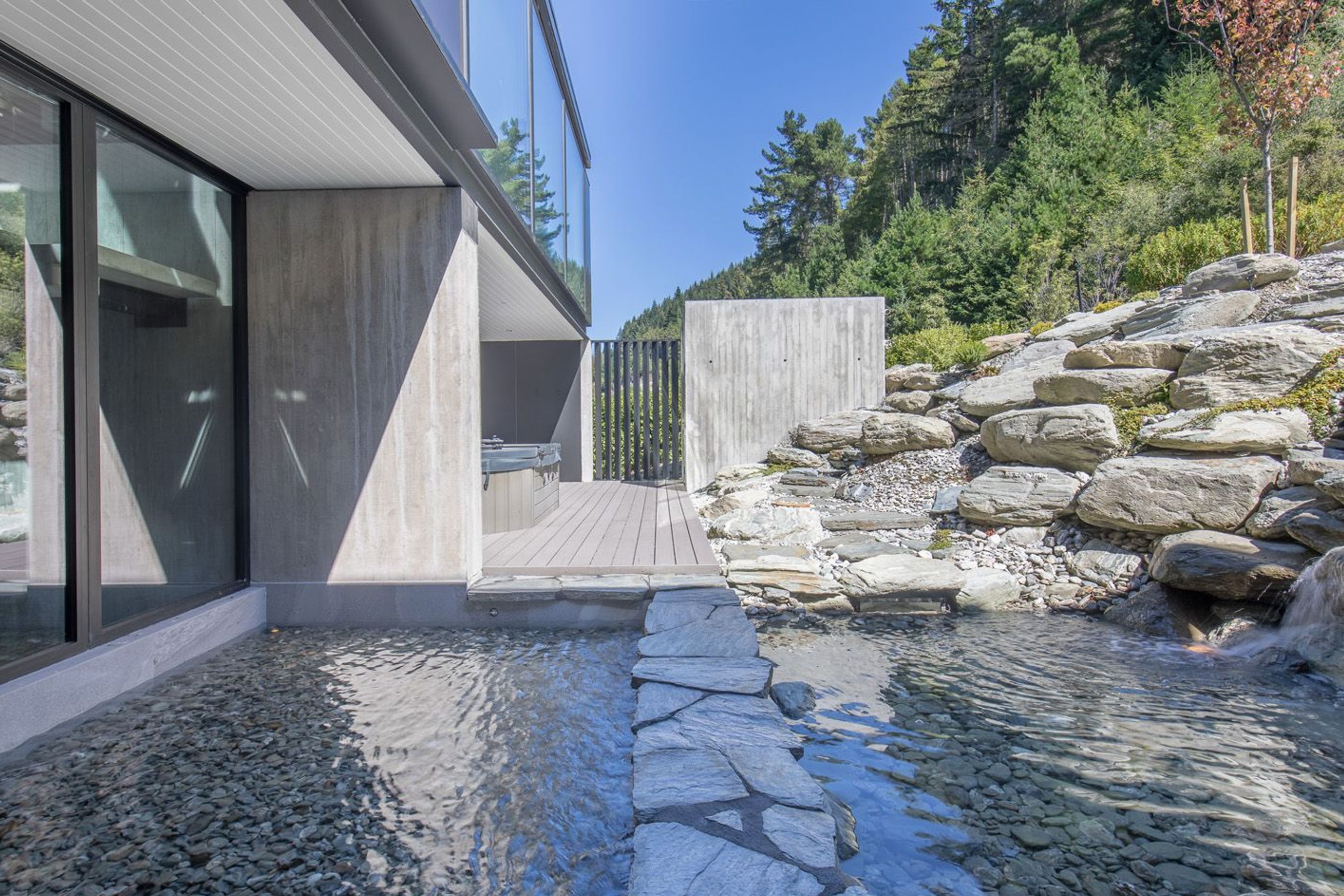 The waterfall trickles in a reflection pond which has a stone path across the middle, which leads to the spa pool and sauna accessed from the hallway to the family bedrooms.
