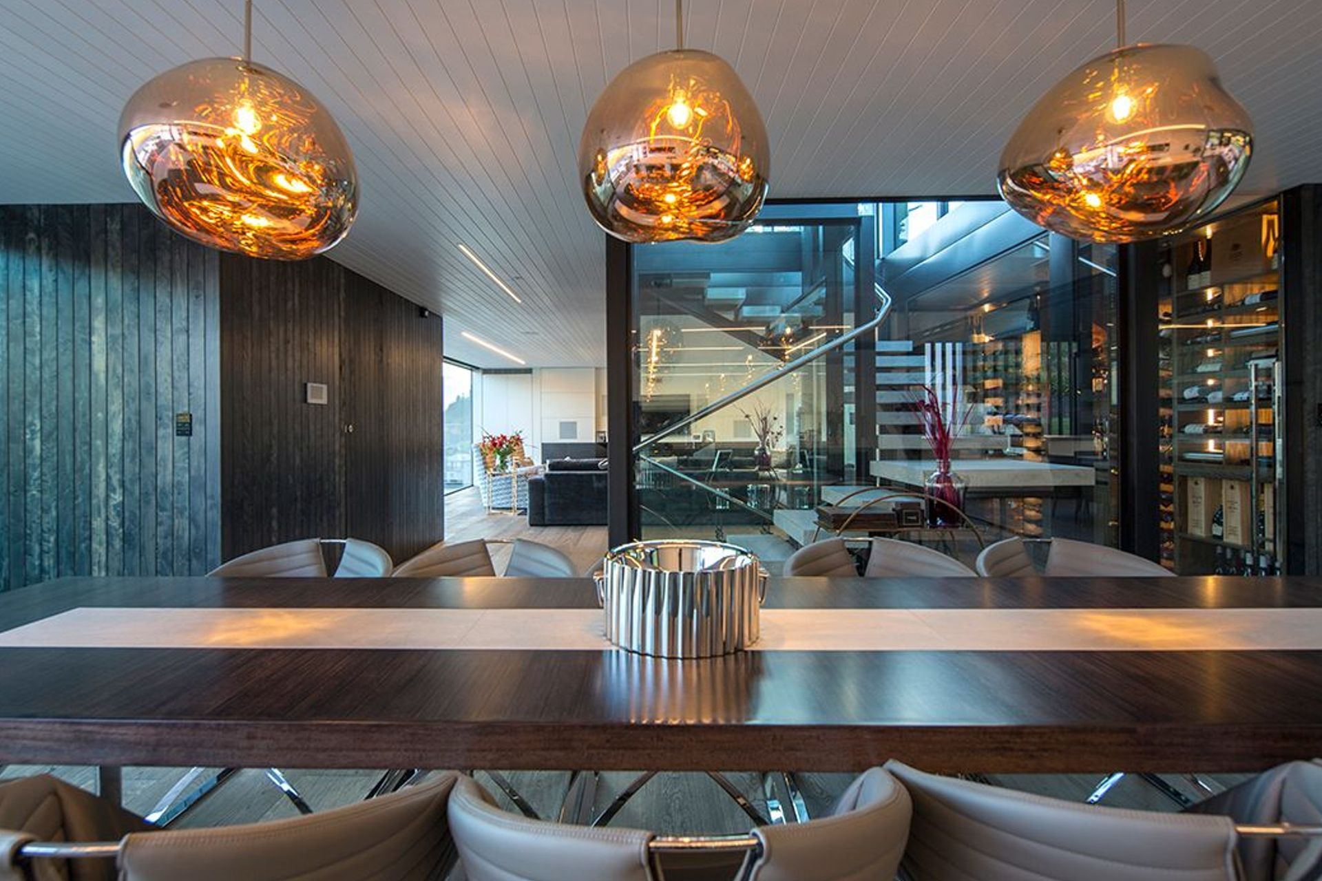 The dining area in the foreground and one of the lounges in the background, seen through the glazed central stairwell. Glass pendants help to define the formal dining space.