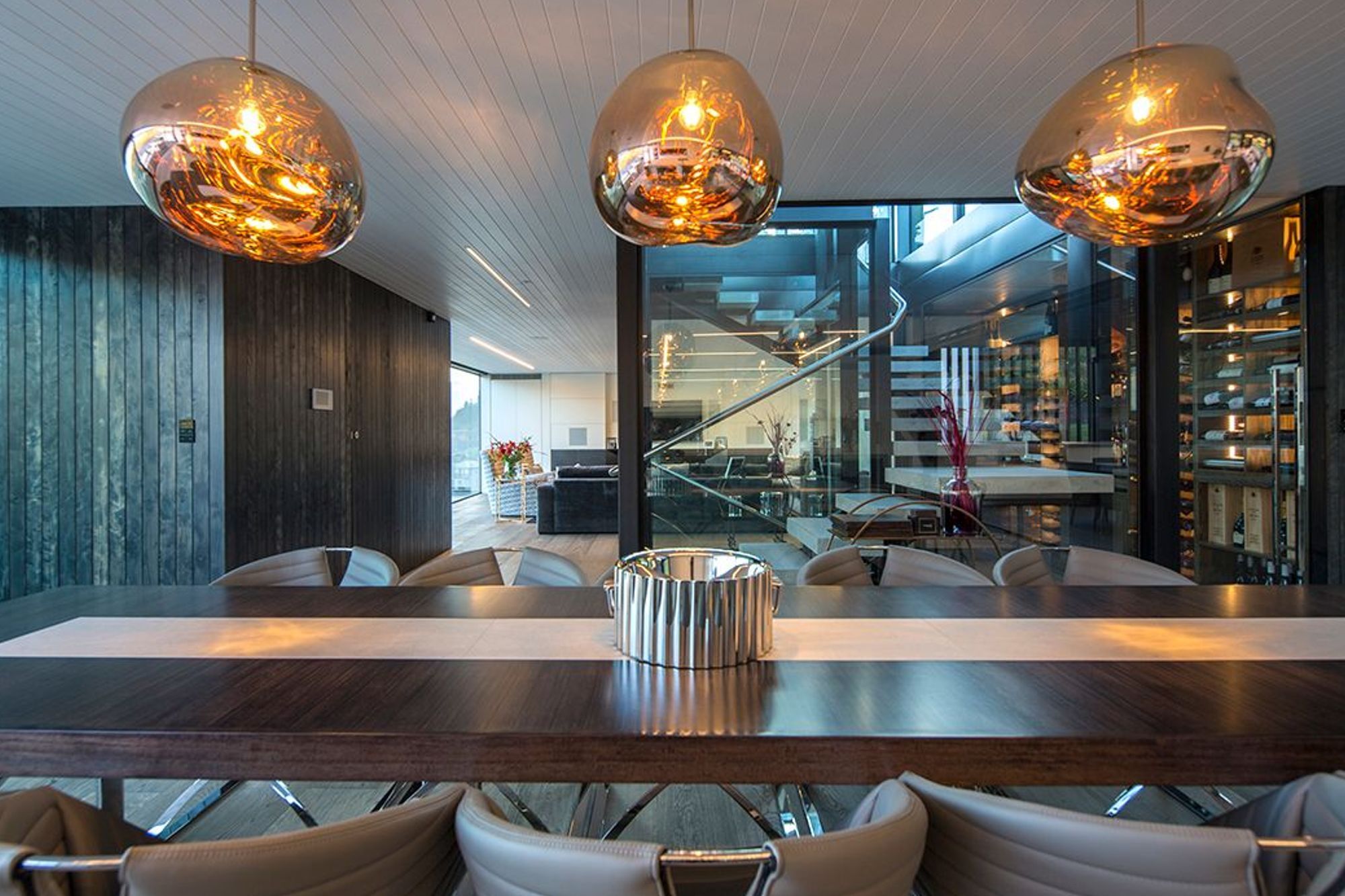 The dining area in the foreground and one of the lounges in the background, seen through the glazed central stairwell. Glass pendants help to define the formal dining space.
