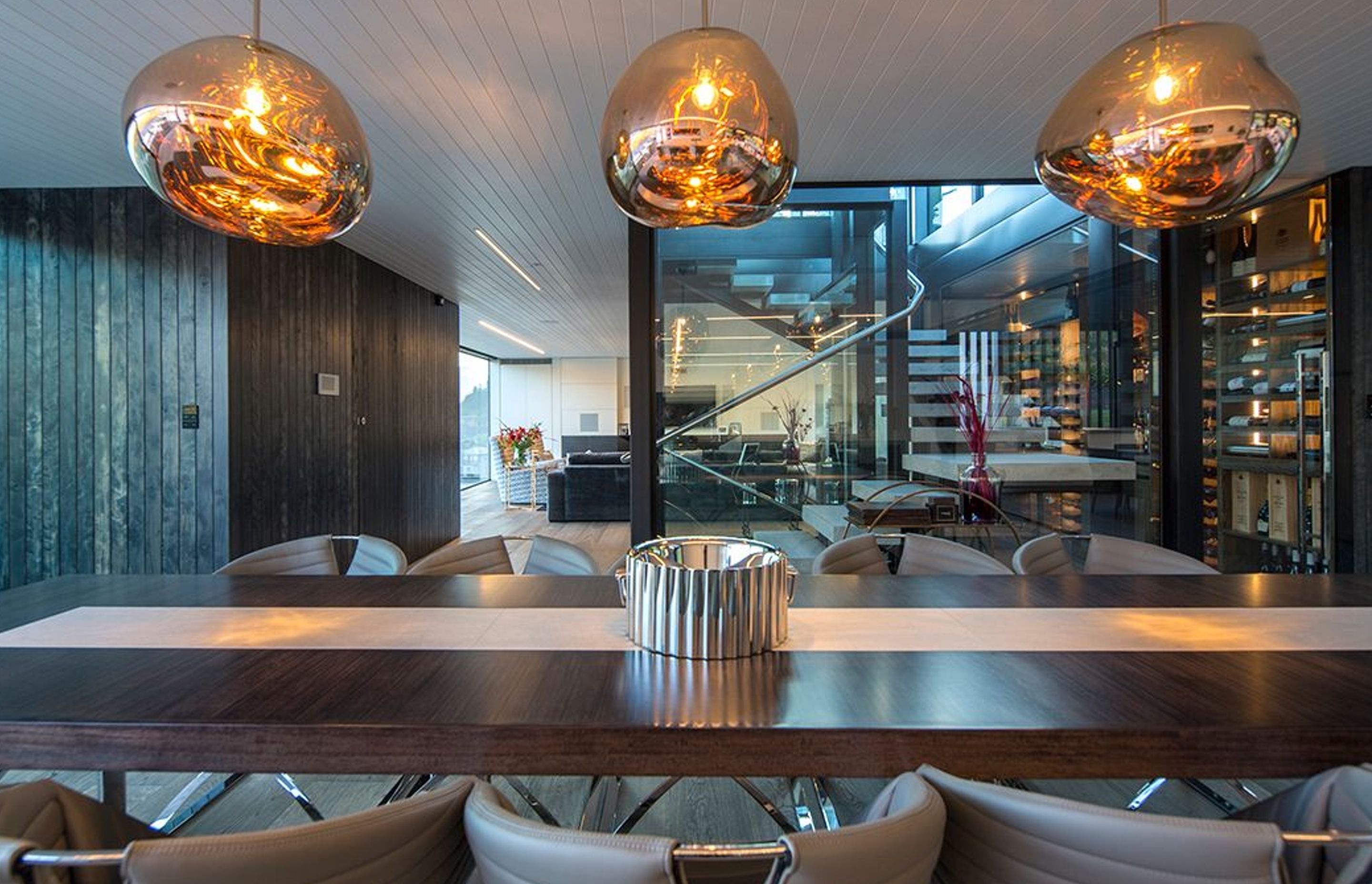 The dining area in the foreground and one of the lounges in the background, seen through the glazed central stairwell. Glass pendants help to define the formal dining space.