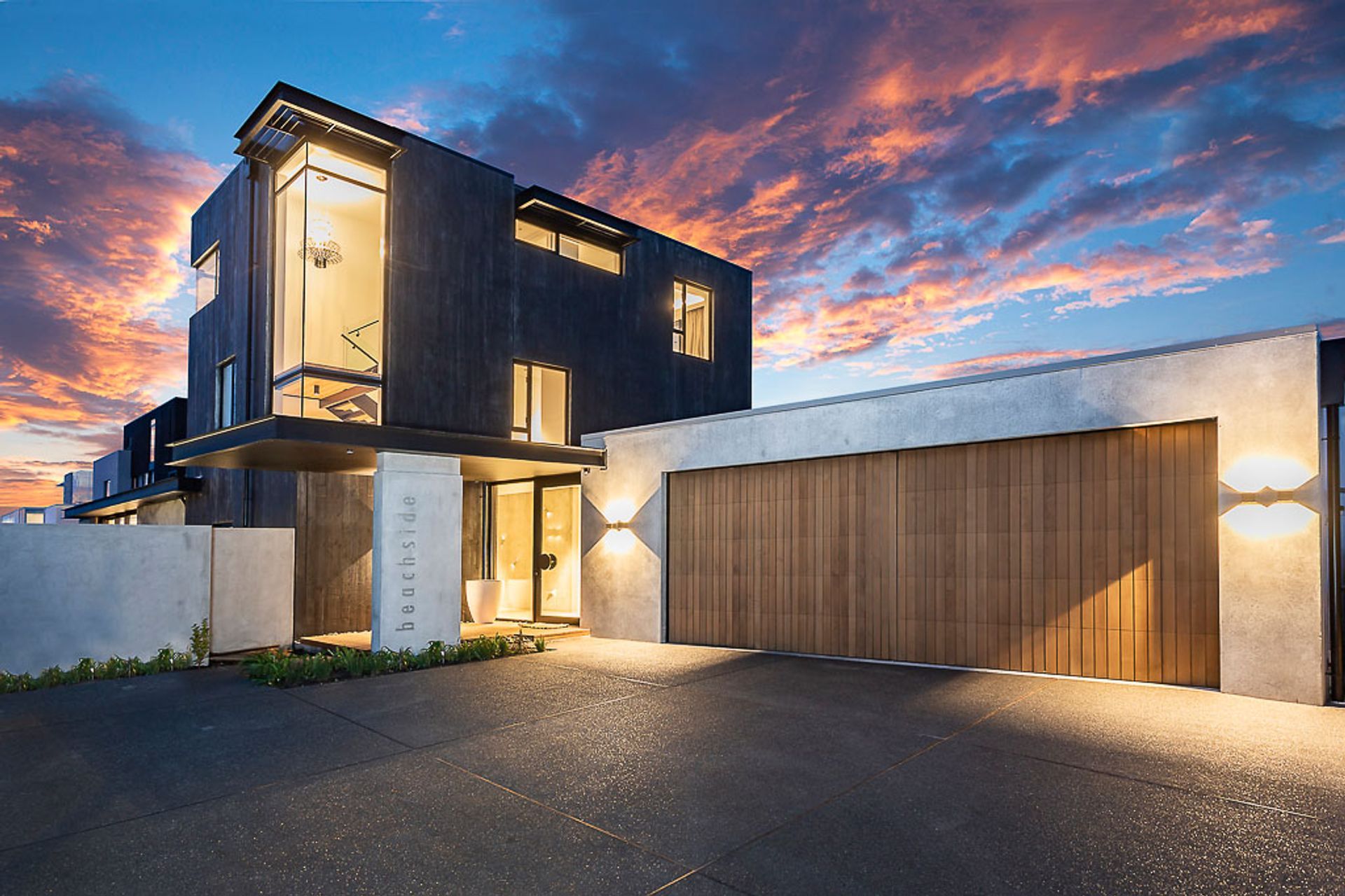 The entry court provides a welcoming mix of materiality, with the cedar garage door and the natural and dyed concrete.