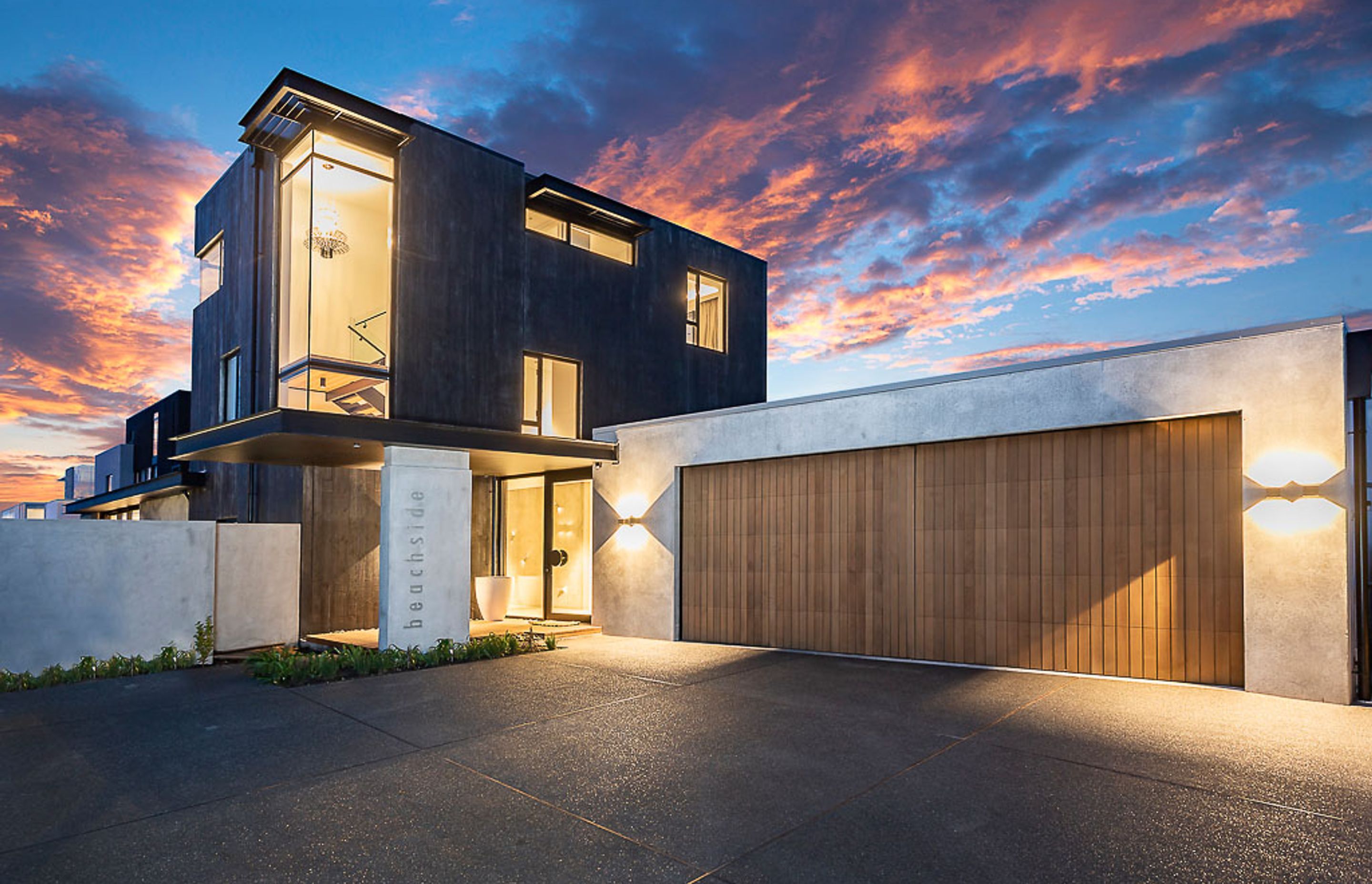The entry court provides a welcoming mix of materiality, with the cedar garage door and the natural and dyed concrete.