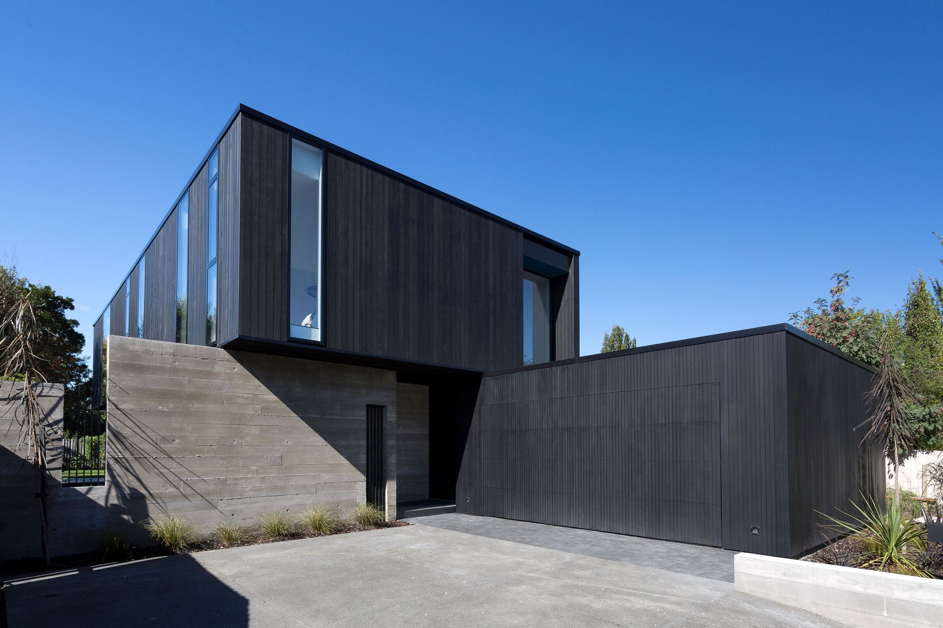 The verticality of the cedar and glass is contrasted by the horizontality of the concrete walls. A discreet garage door becomes a flat black cedar wall when closed.