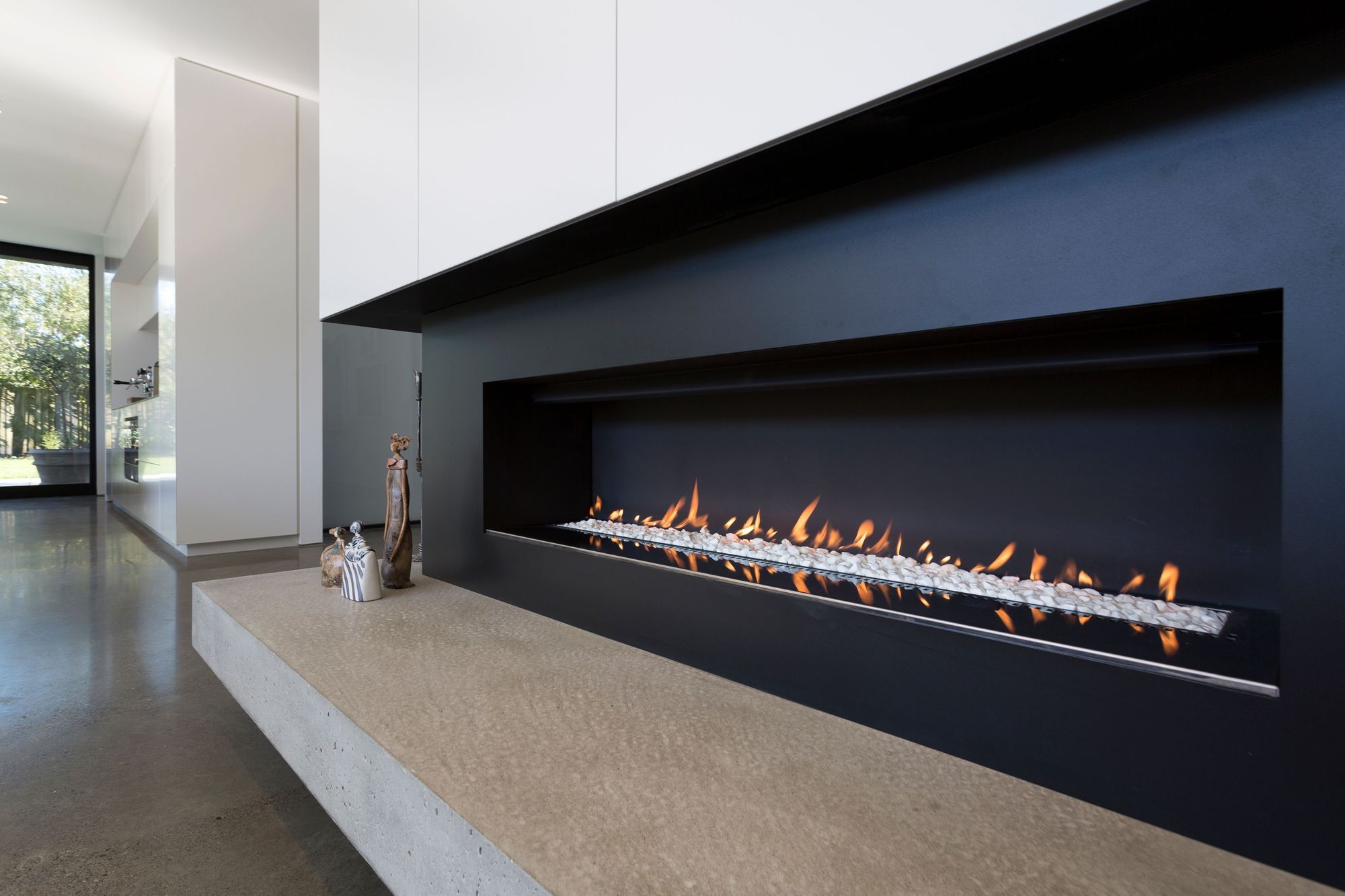 In the lounge area, the fireplace has all-black surrounds with a solid concrete hearth.
