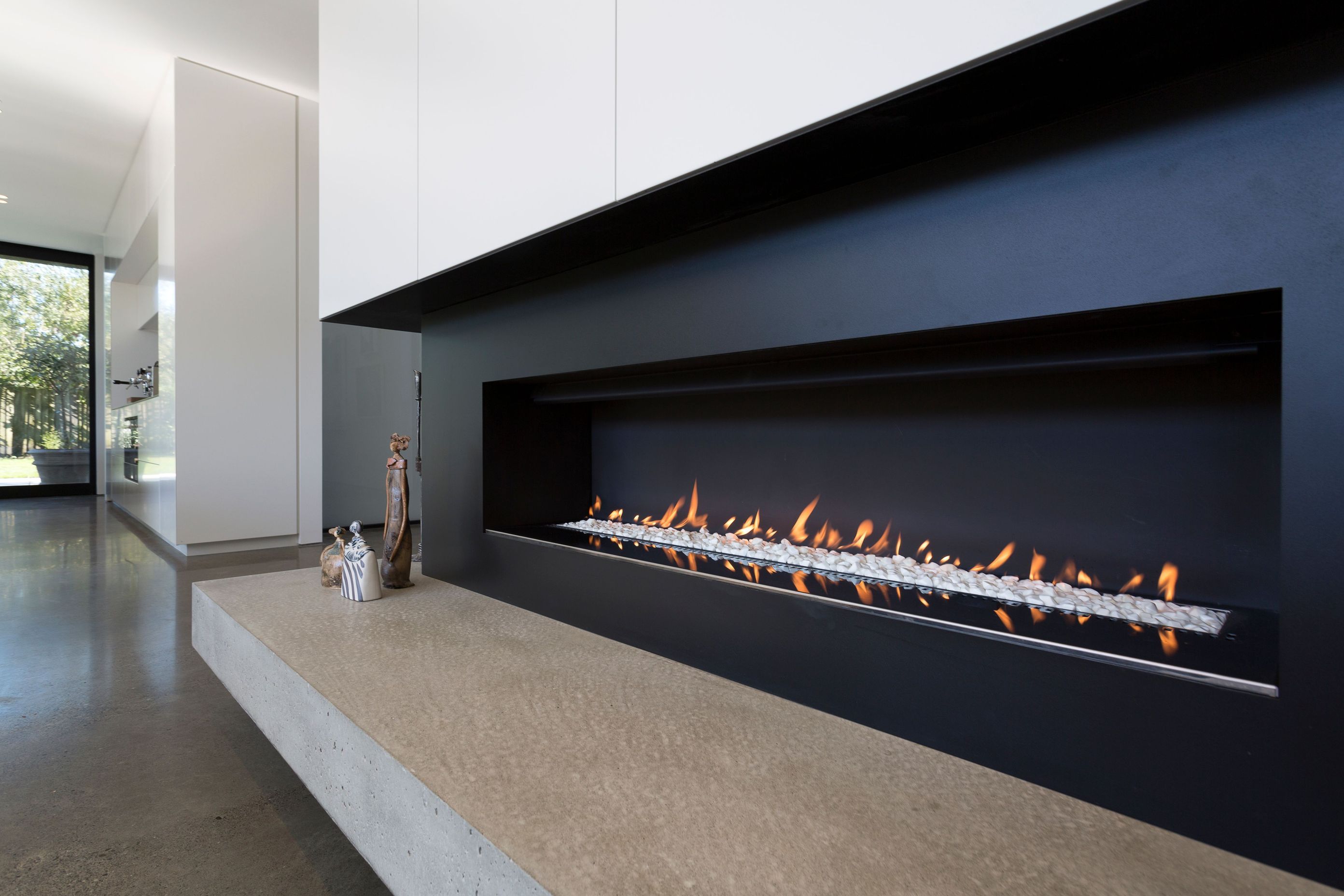 In the lounge area, the fireplace has all-black surrounds with a solid concrete hearth.