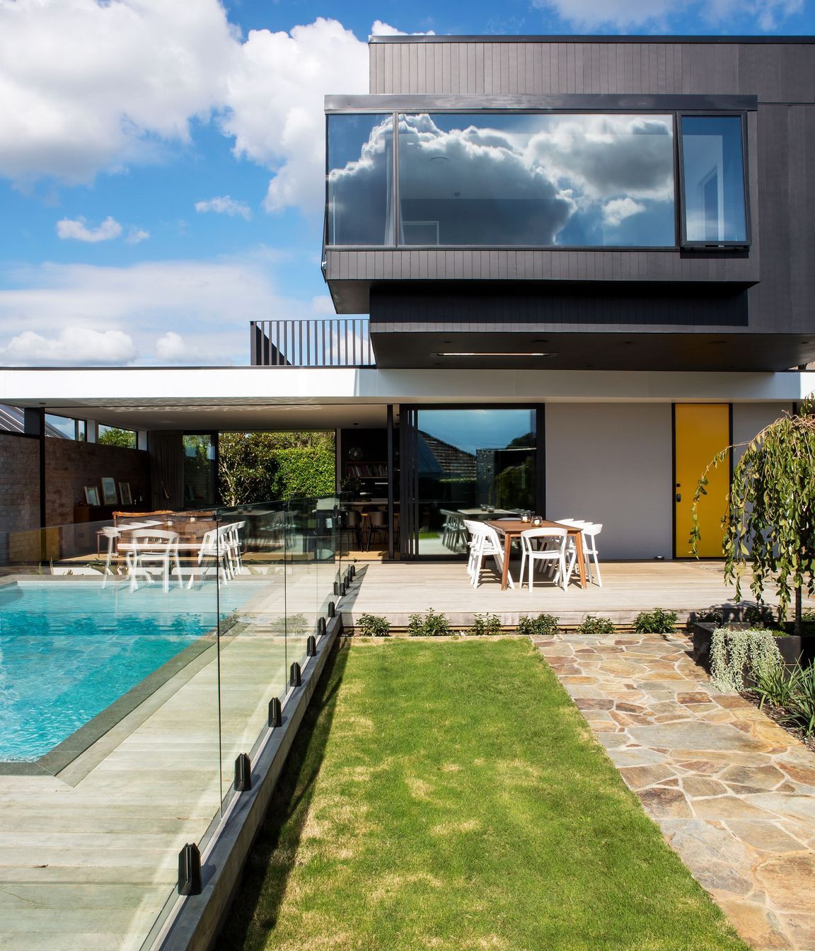 In modernist style, a big black box perches over a white aluminium roof plane, creating a crucifix-like plan.