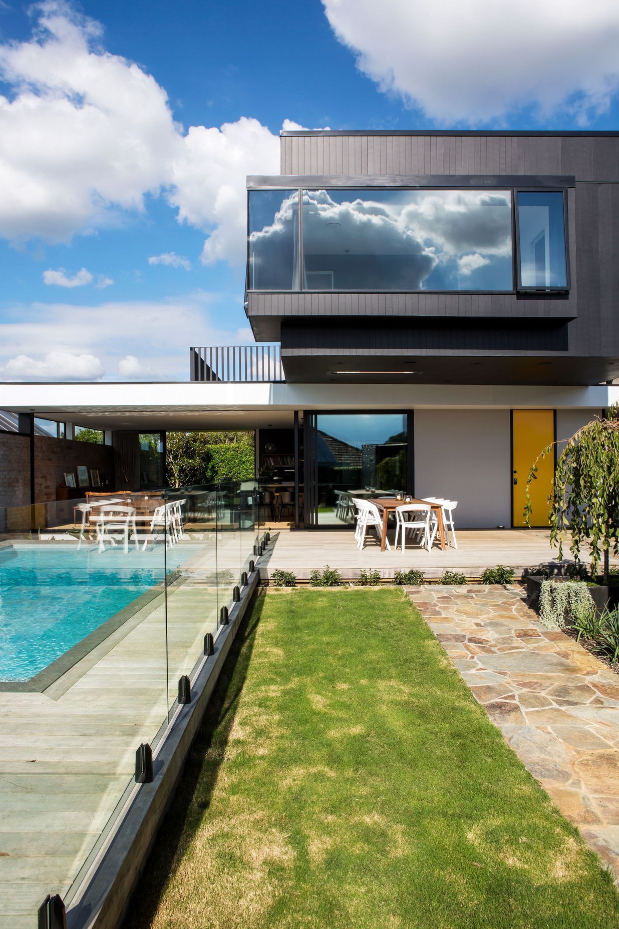 In modernist style, a big black box perches over a white aluminium roof plane, creating a crucifix-like plan.