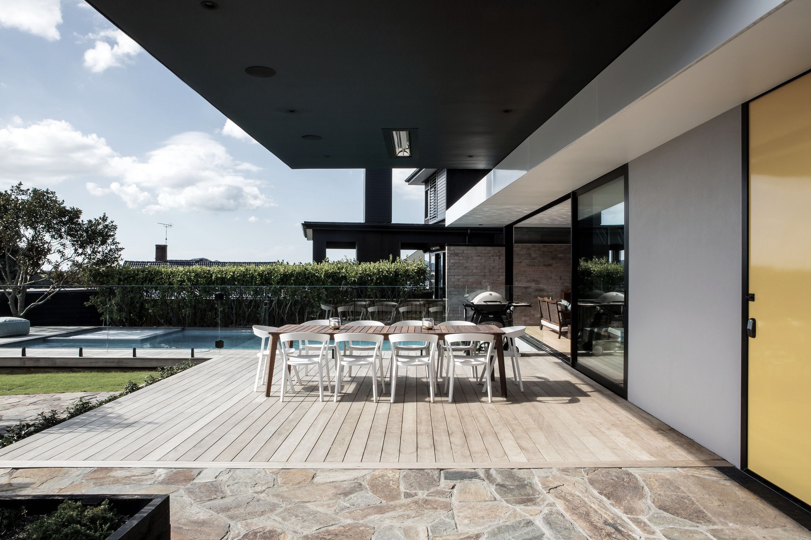 This modernist-inspired home includes bright yellow accents and crazy paving that runs from the front patio area, seen here, indoors to the entry.