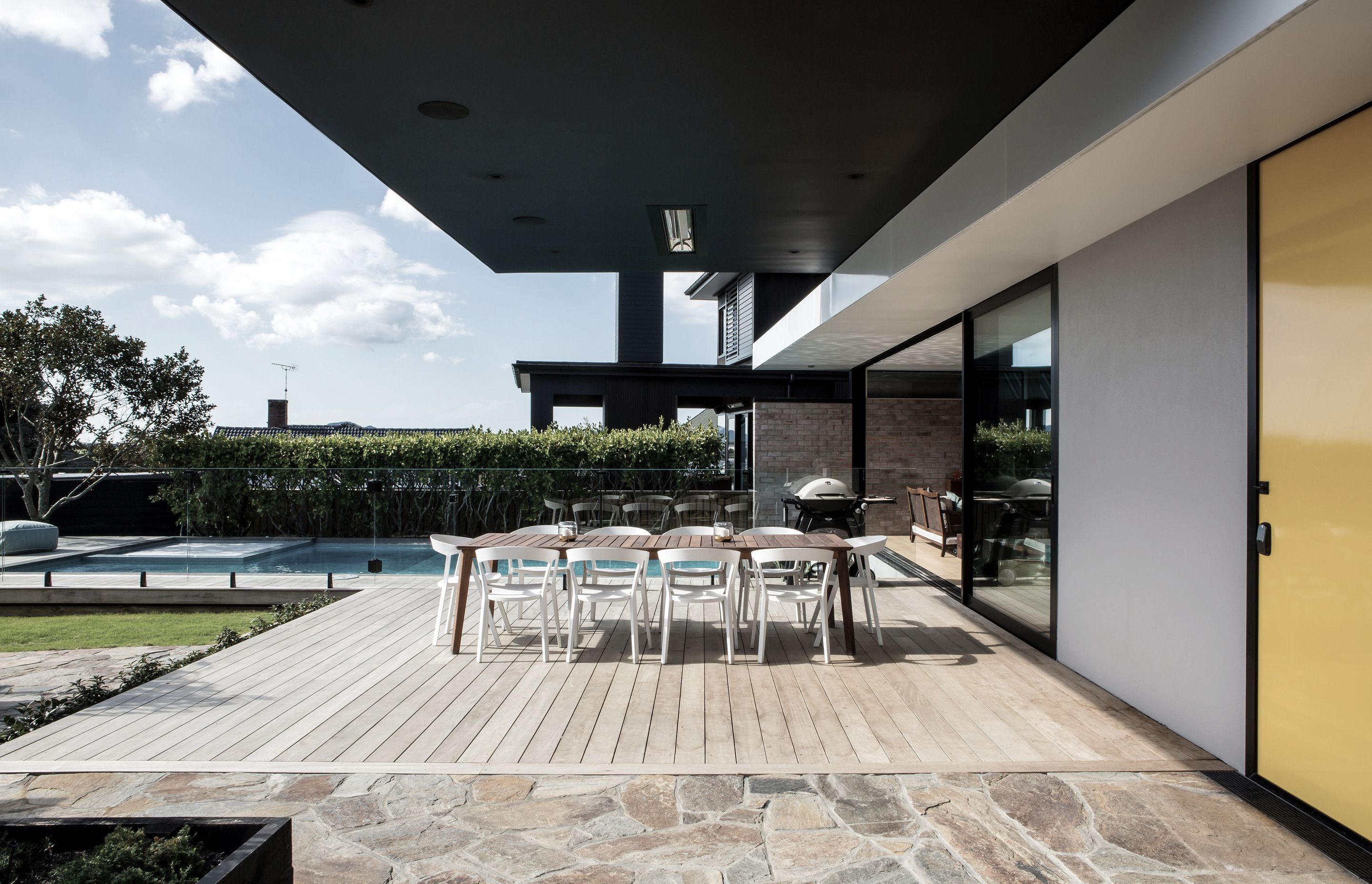 This modernist-inspired home includes bright yellow accents and  crazy paving that runs from the front patio area, seen here, indoors to the entry.